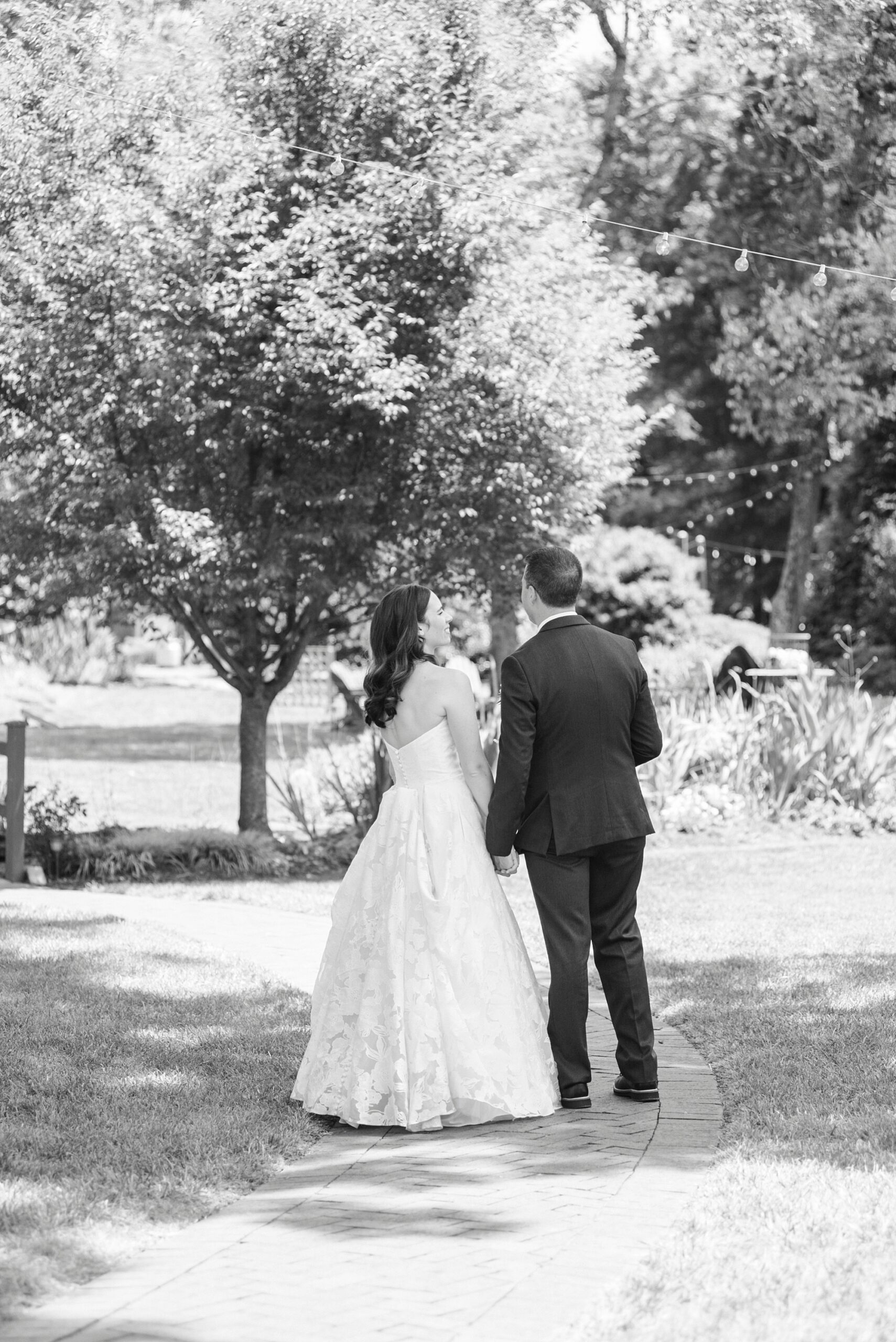 bride and groom hold hands walking down path at Alexander Homestead