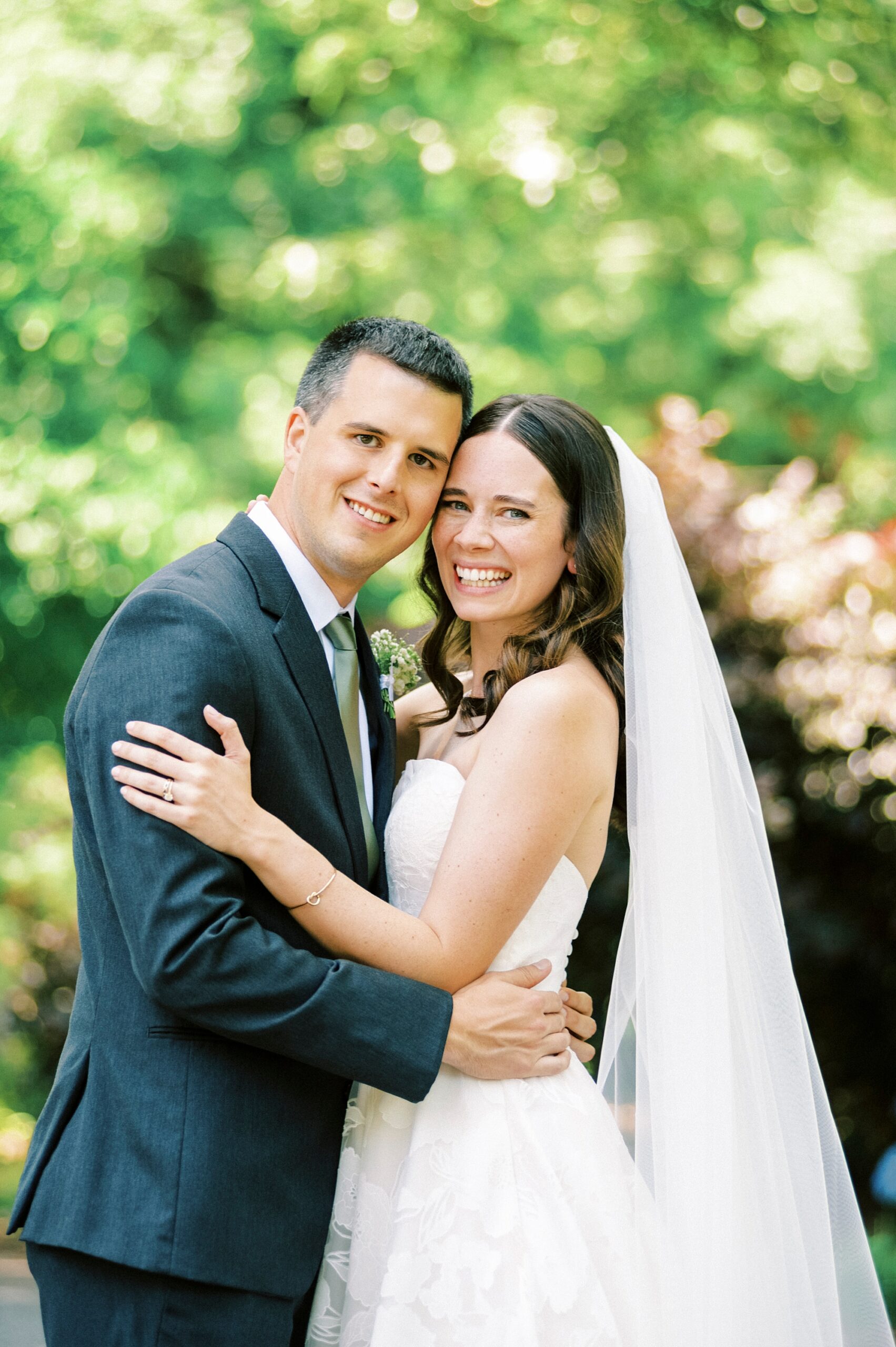 newlyweds smile leaning heads together on pathway in gardens of Alexander Homestead