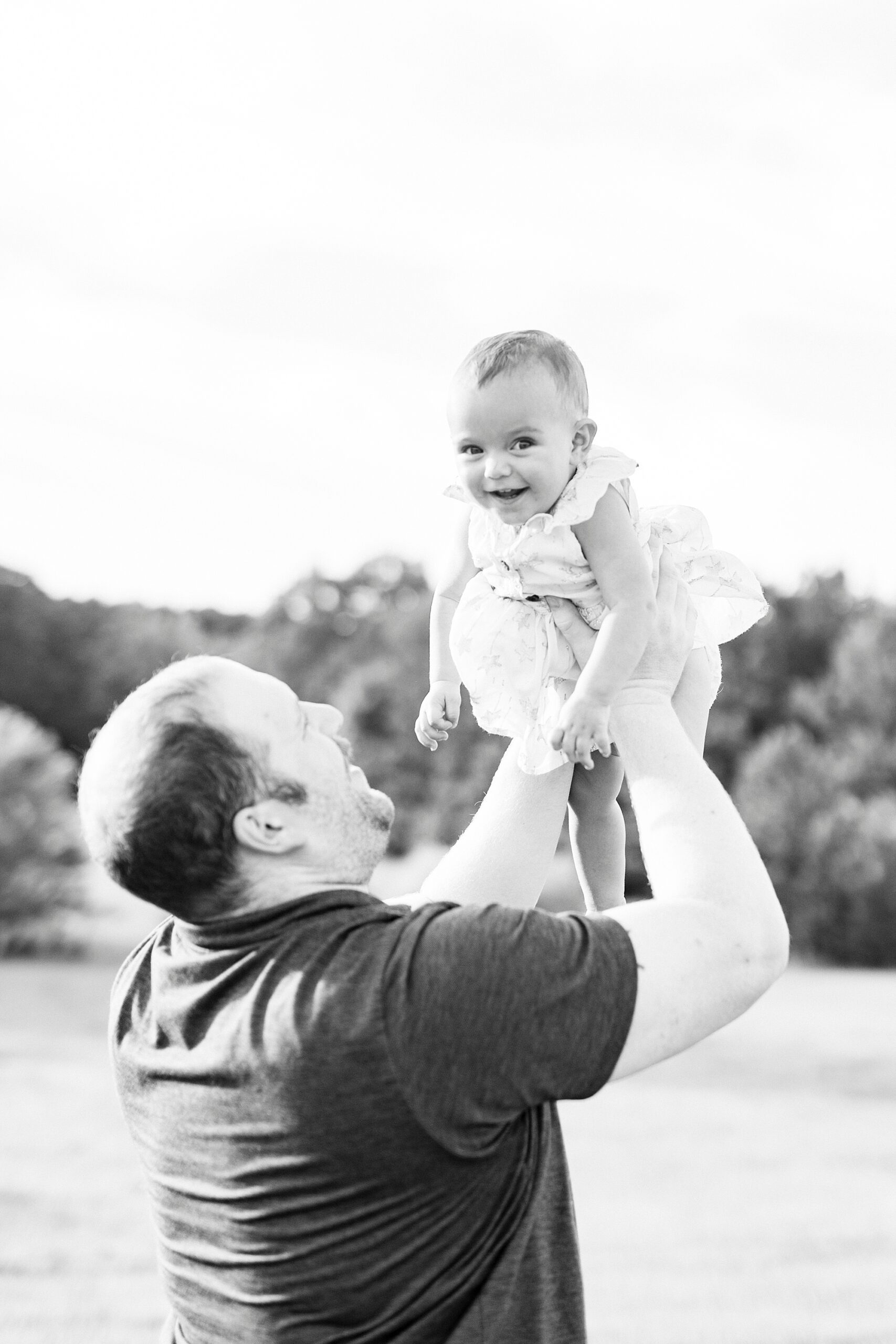 dad lifts up toddler on family farm in Albemarle during first birthday portraits 
