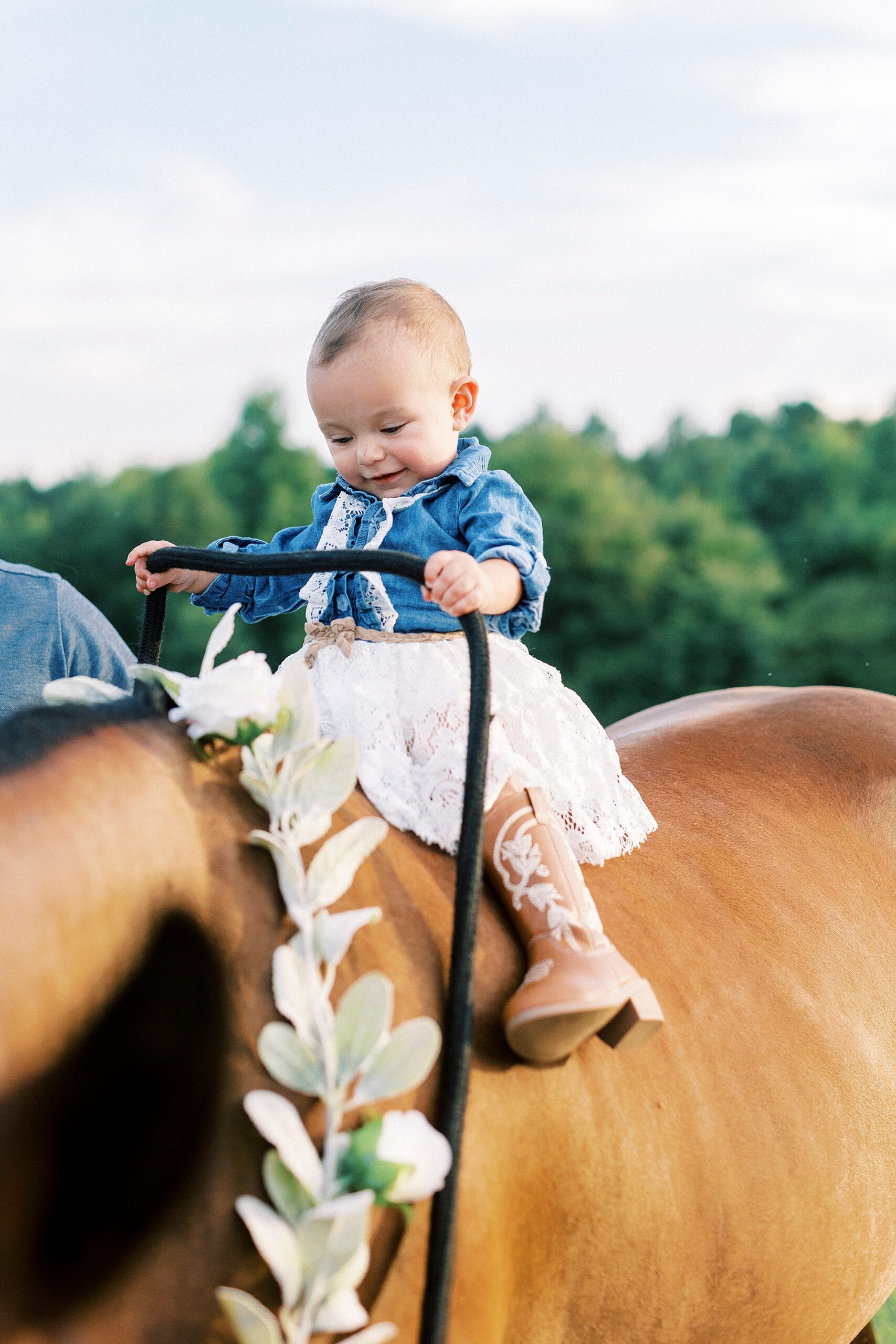 girl rides on back of brown horse during first birthday portraits in Albemarle NC