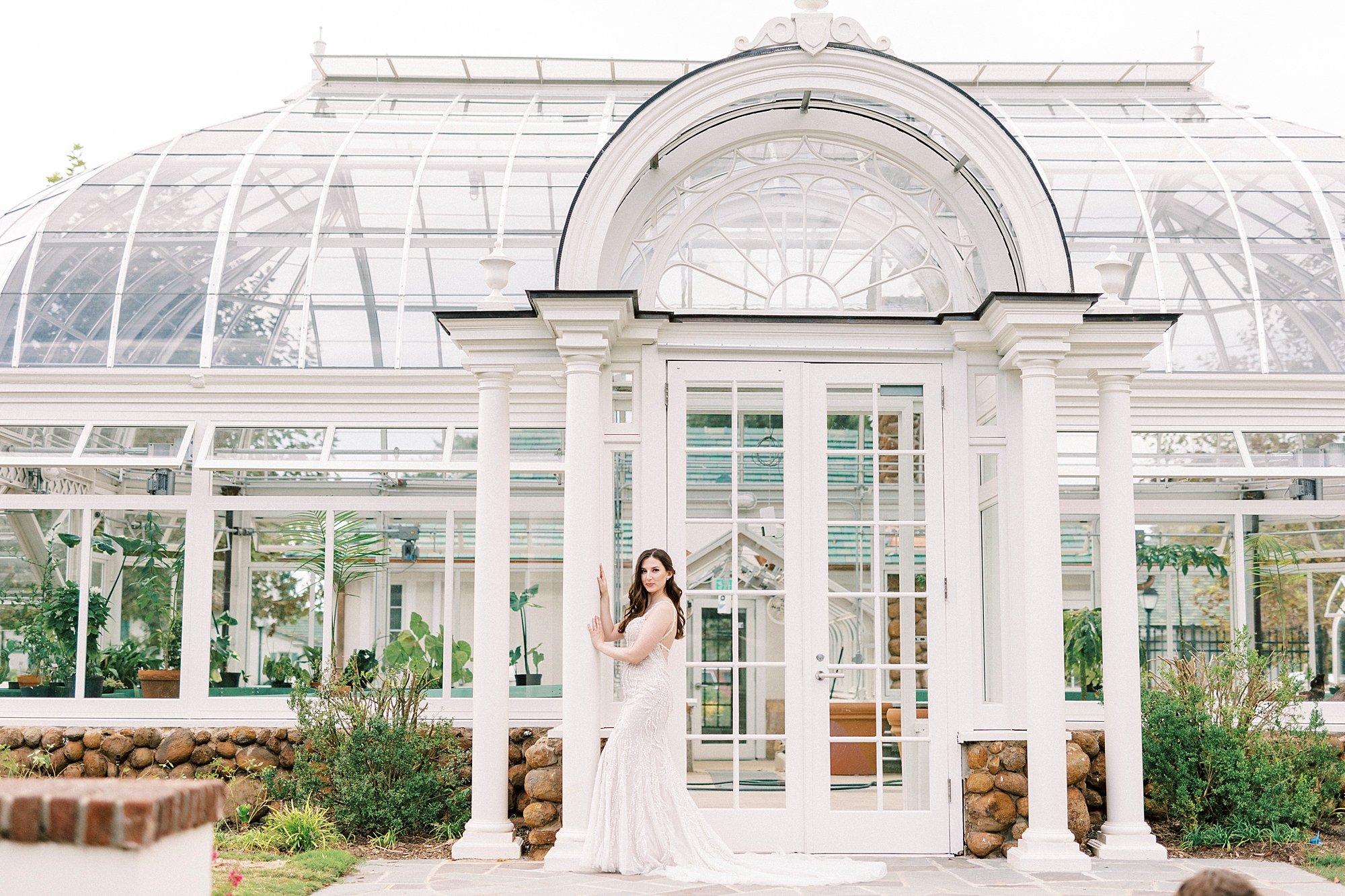 bride poses against pillar of greenhouse at Reynolda Gardens