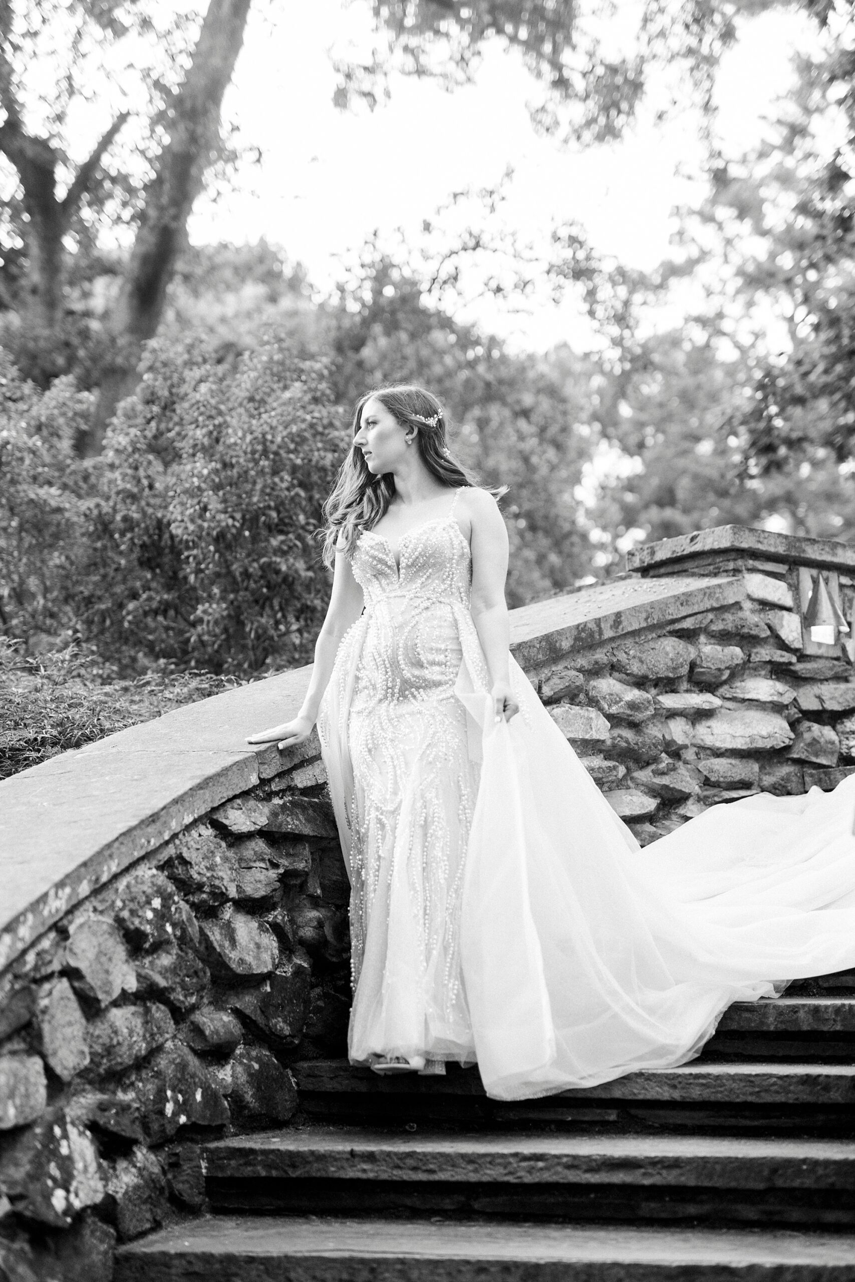 bride smiles over railing of stone staircase at the Graylyn Estate