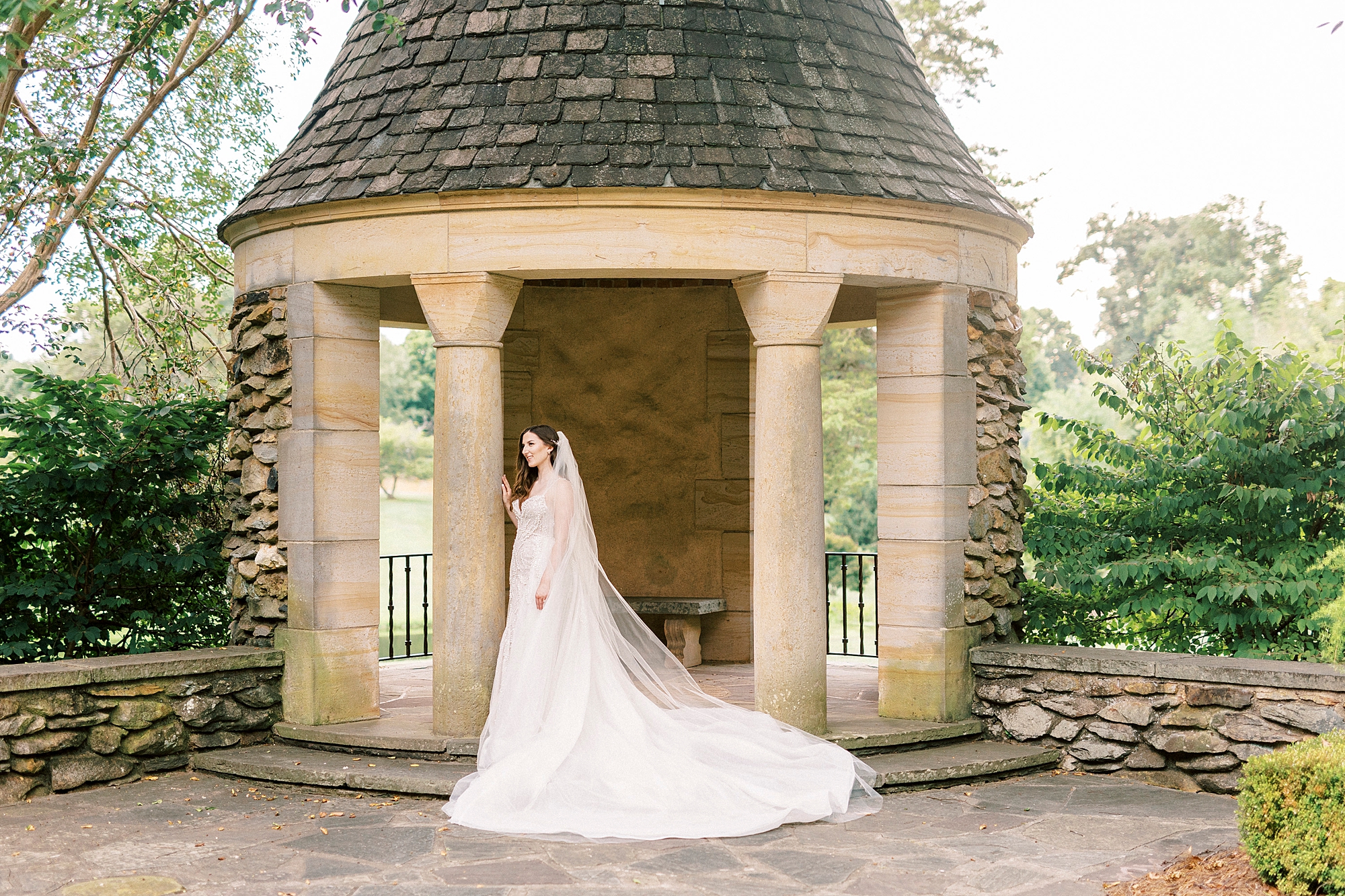 bride poses by gazebo at the Graylyn Estate