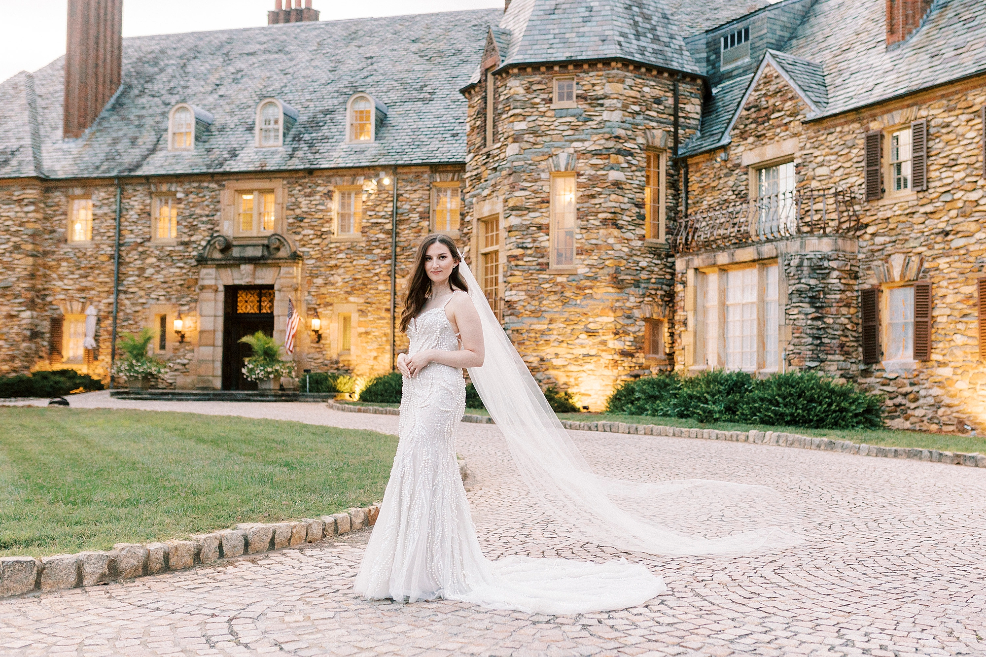 bride poses in front of the Graylyn Estate with veil pulled out behind her