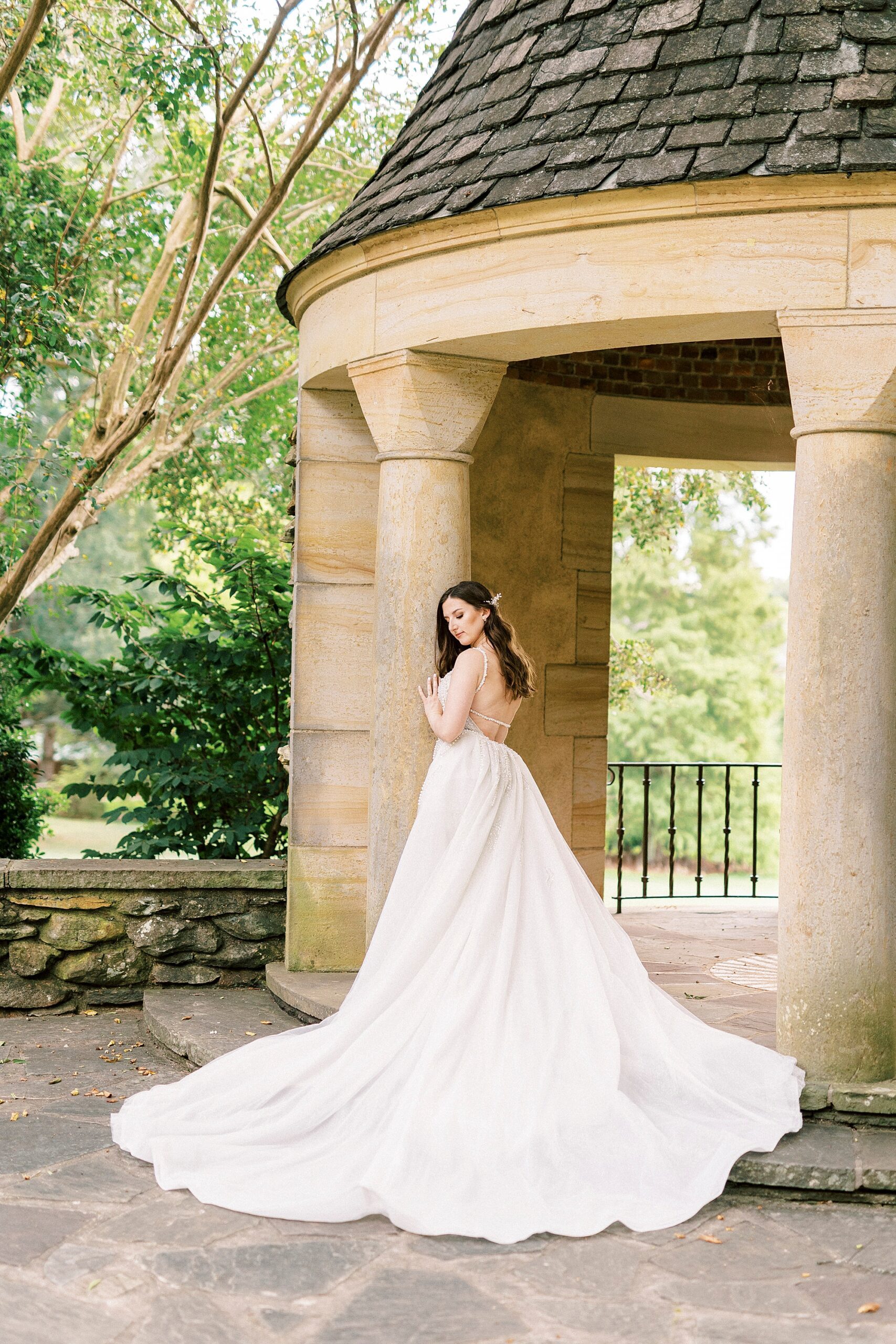 bride looks down over her shoulder with wedding gown laid out behind her at the Graylyn Estate