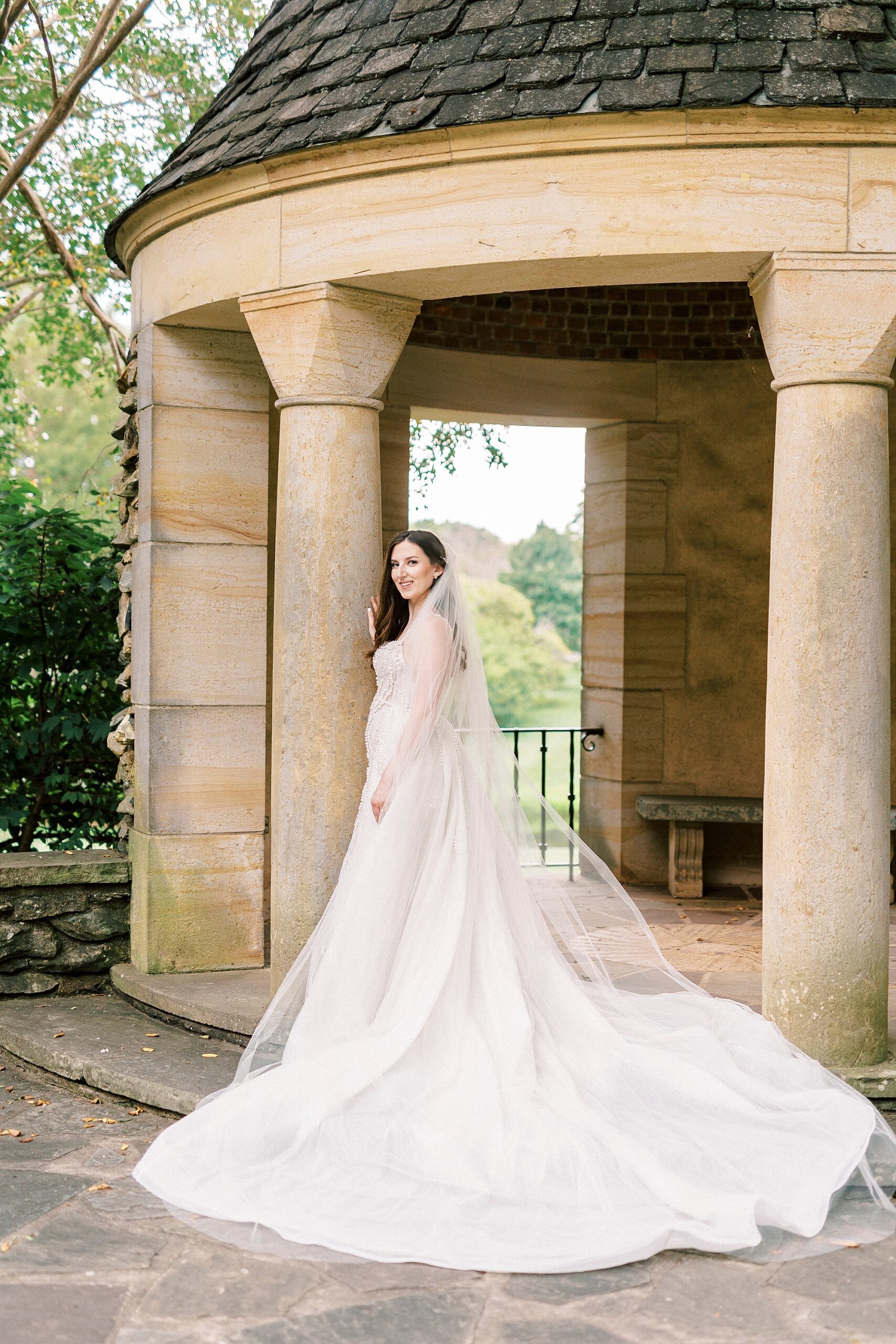 bride smiles looking over her shoulder standing by the Graylyn Estate gazebo