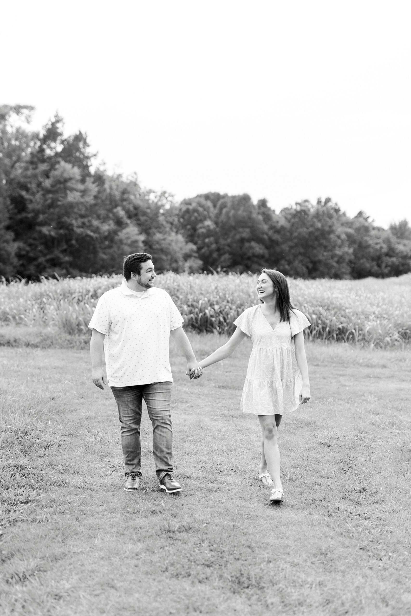 couple walks holding hands and laughing outside home in Kannapolis NC
