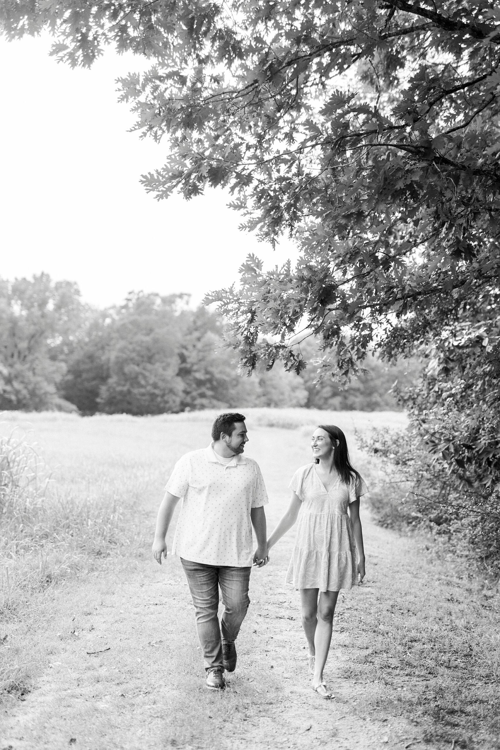 engaged couple walks down dirt path during Kannapolis NC engagement session at home