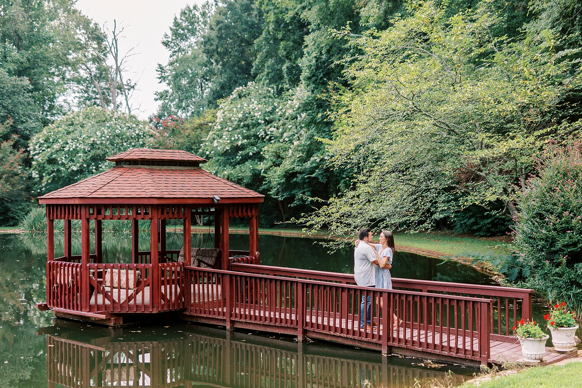engaged couple hugs on bridge on water during Kannapolis NC engagement session