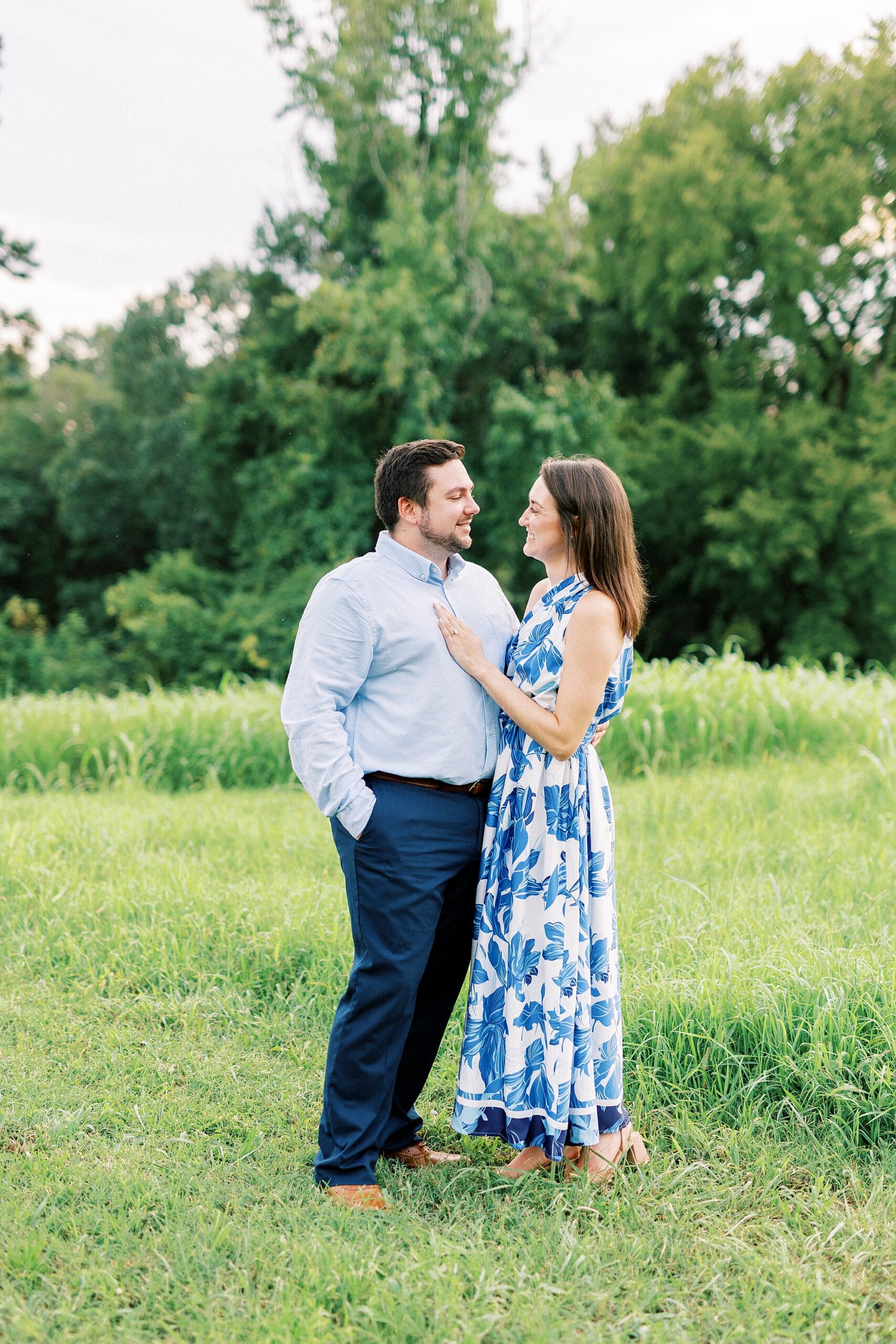 man and woman hug on edge of field during Kannapolis NC engagement session