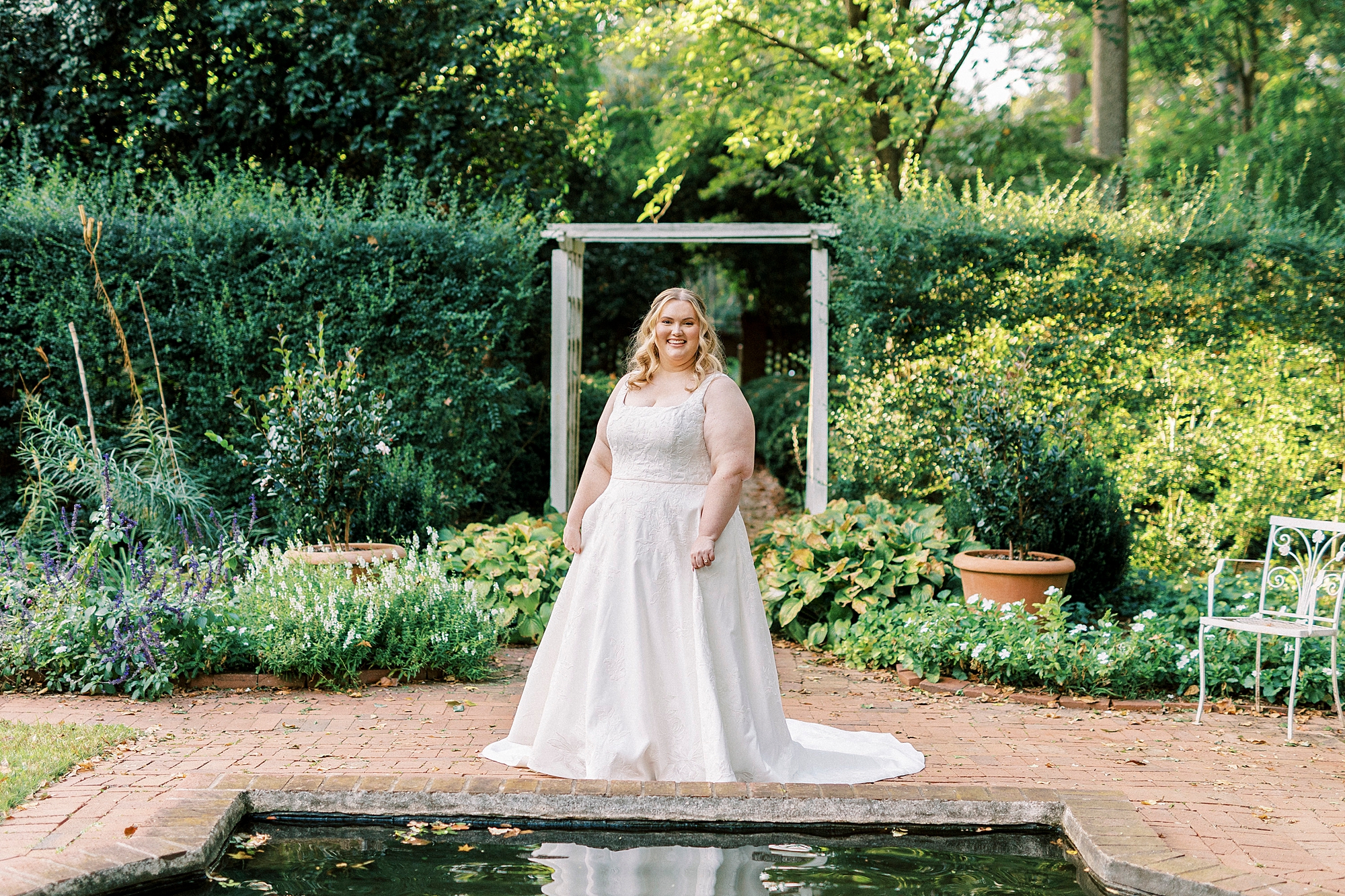 bride stands inside Wing Haven Gardens near reflecting pond