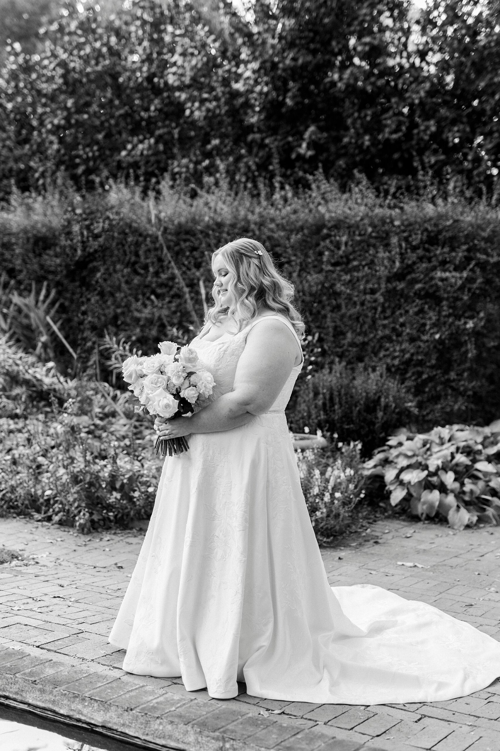 bride looks down at bouquet of white flowers during bridal portraits at Wing Haven Gardens