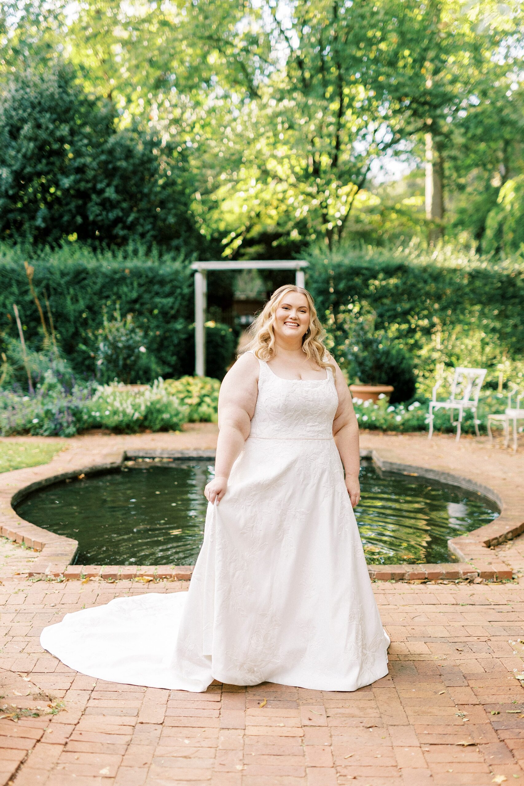 bride smiles holding skirt of wedding dress during Charlotte bridal portraits 