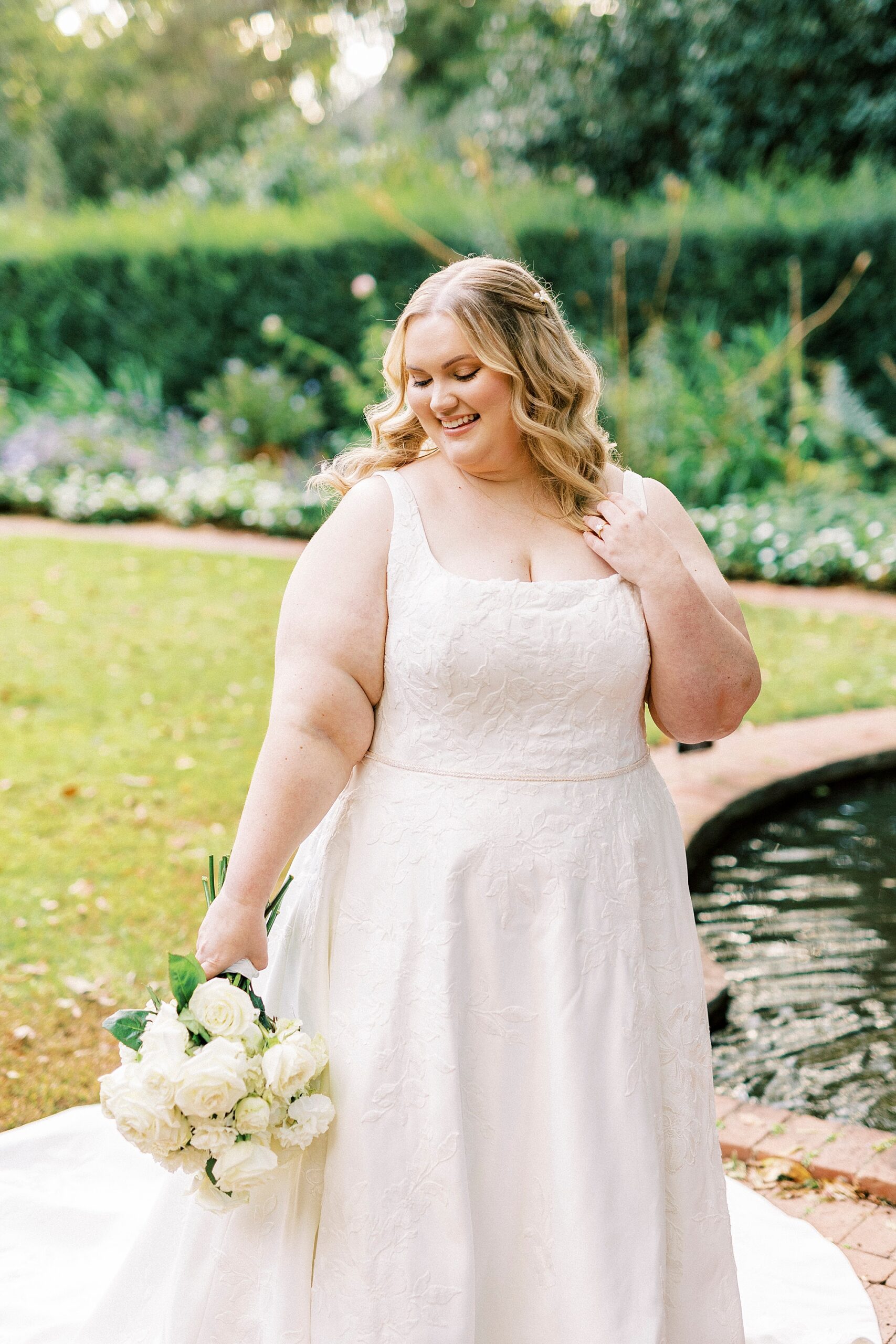 bride smiles standing by pond in Charlotte NC gardens