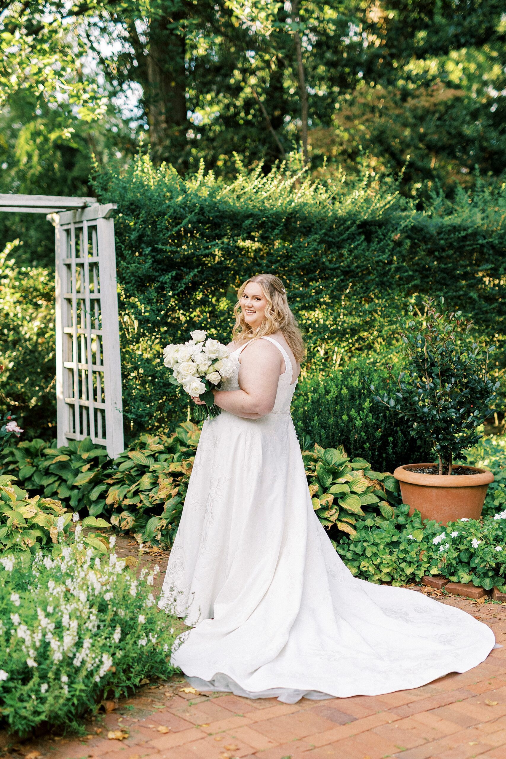 bride smiles over shoulder holding ivory bouquet of roses 