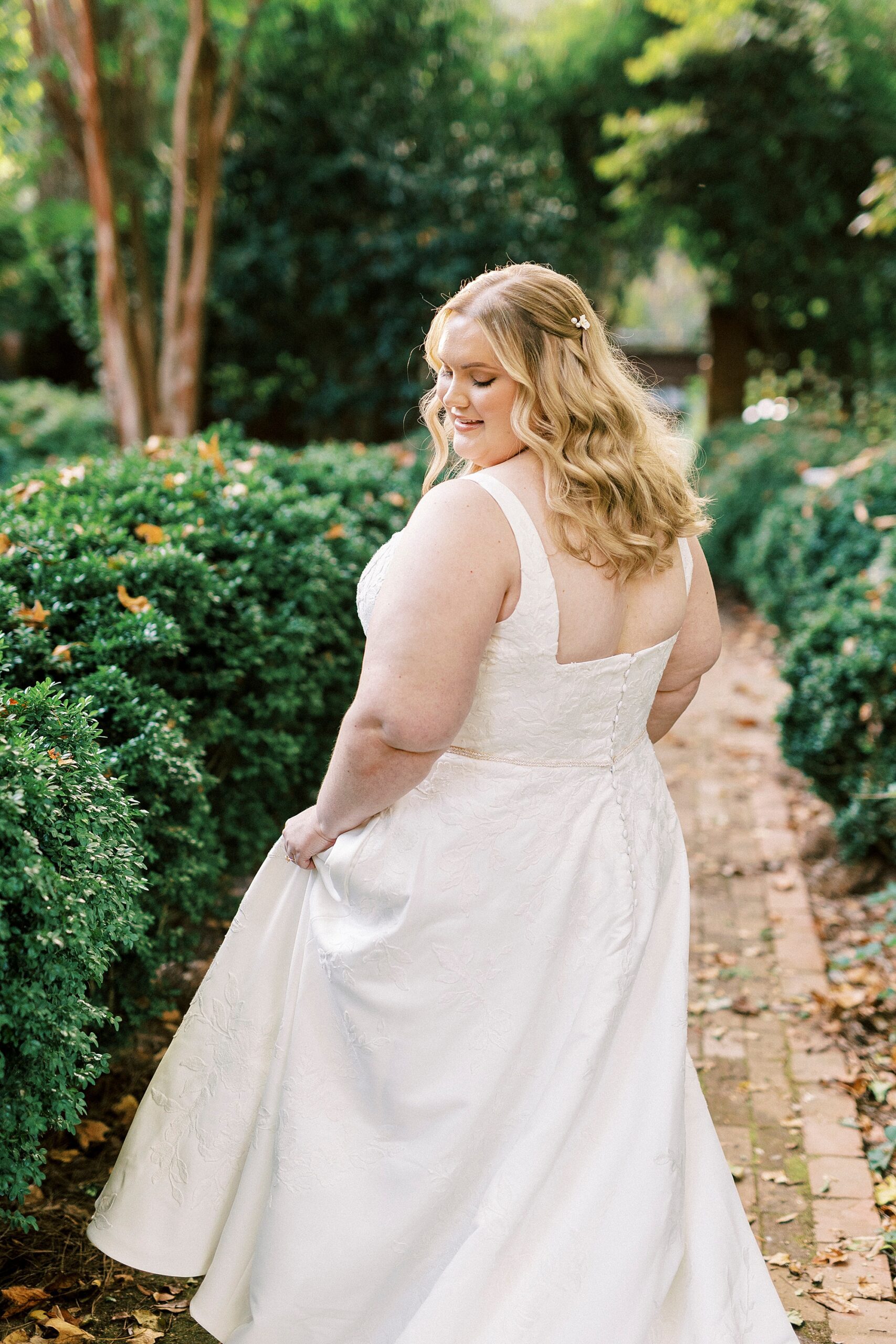 bride walks down brick pathway inside Charlotte NC gardens 