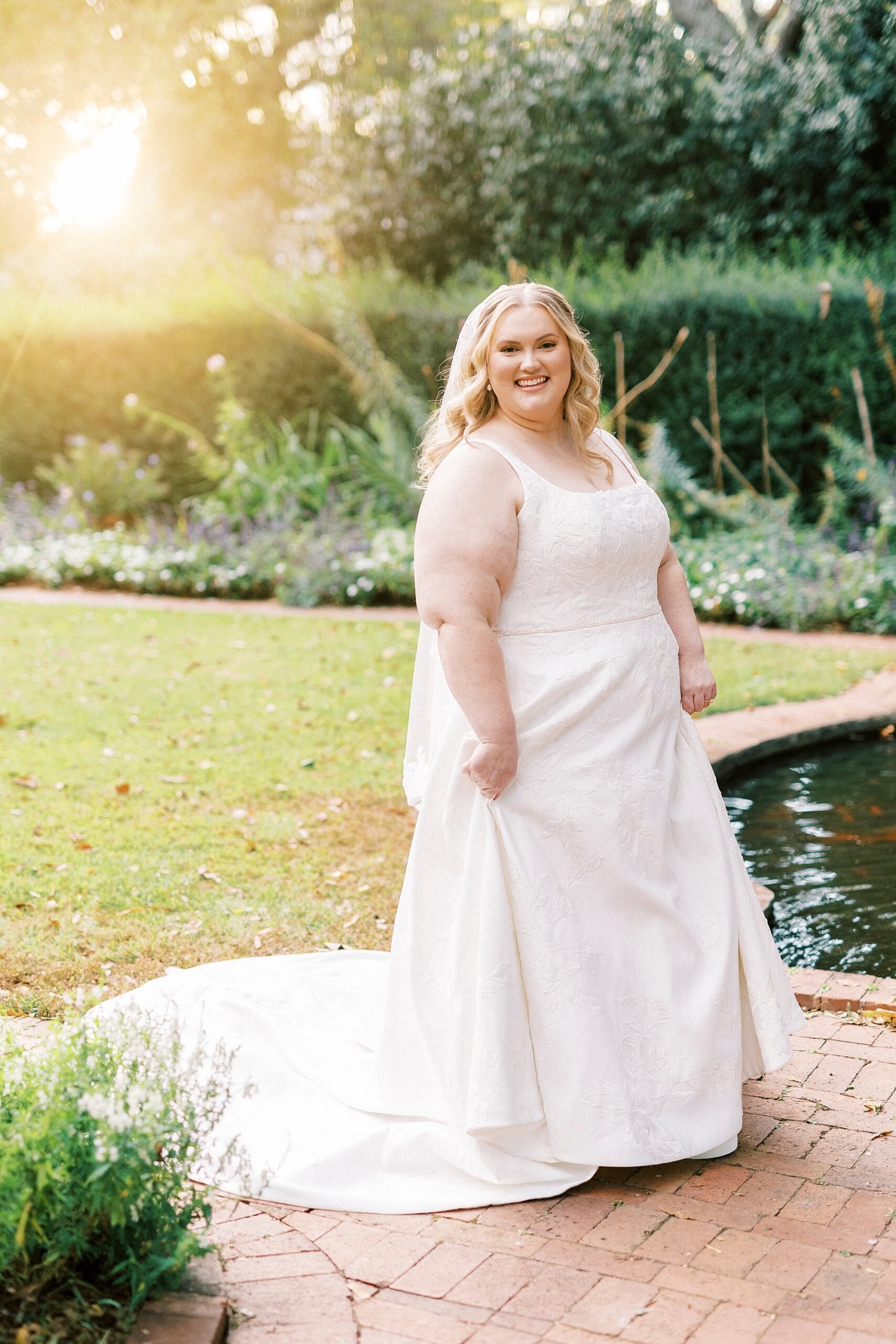 bride twirls in wedding dress by pond inside Wing Haven Gardens