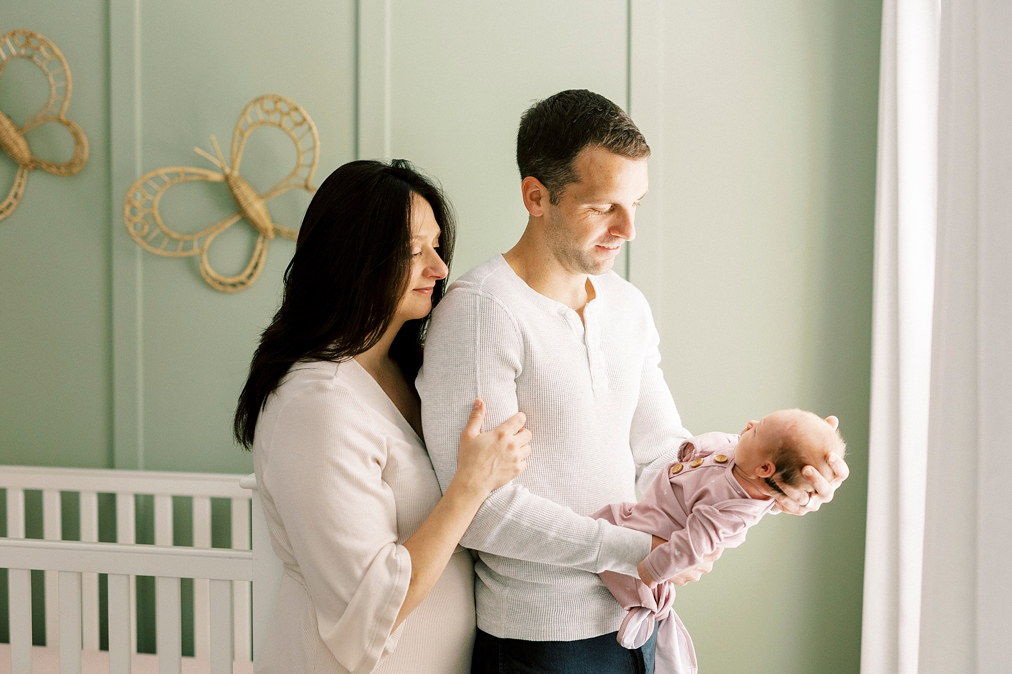 dad holds new daughter in his hands with mom looking over his shoulder