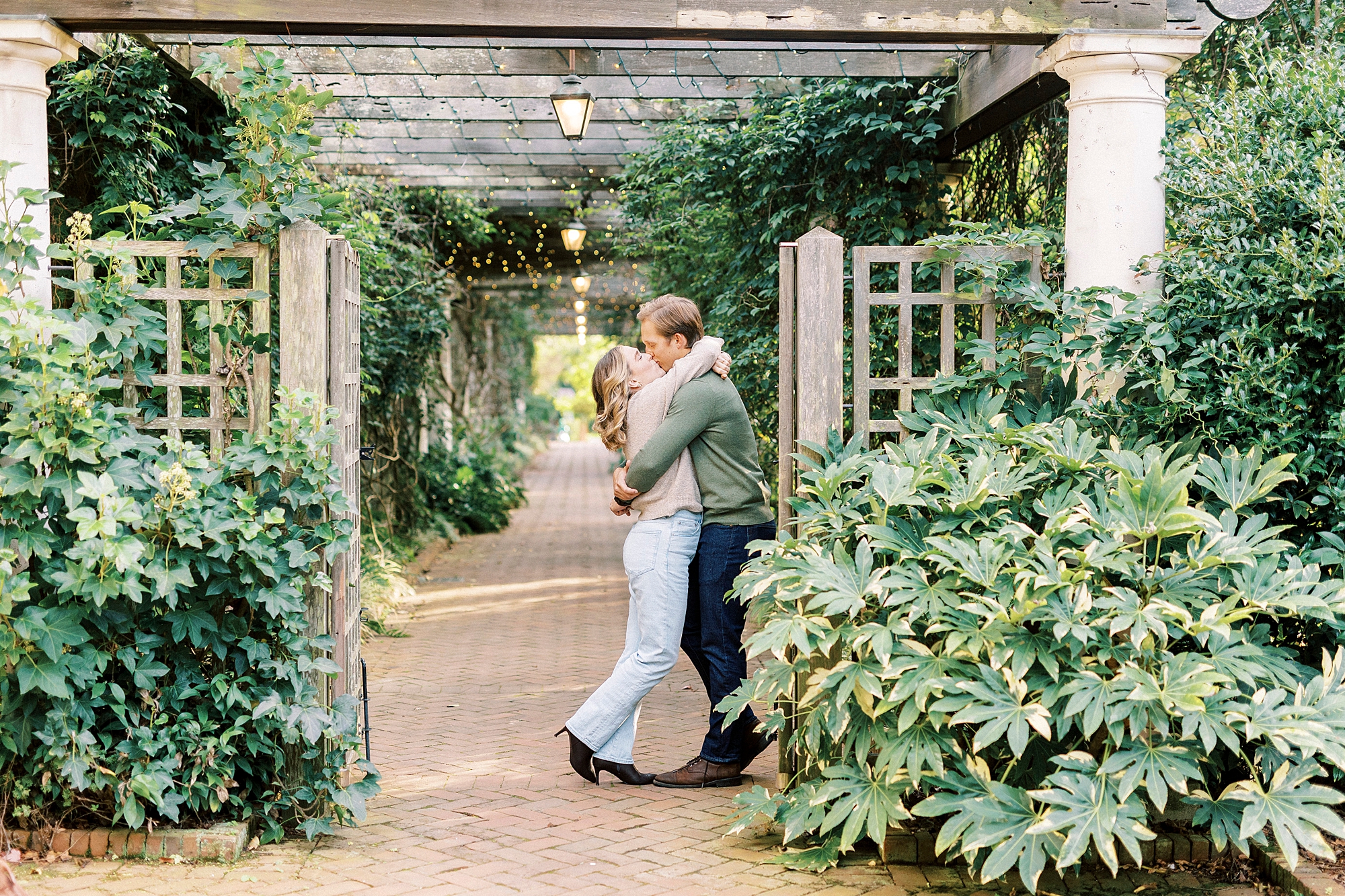 man and woman hug between wooden gate inside Daniel Stowe Botanical Garden