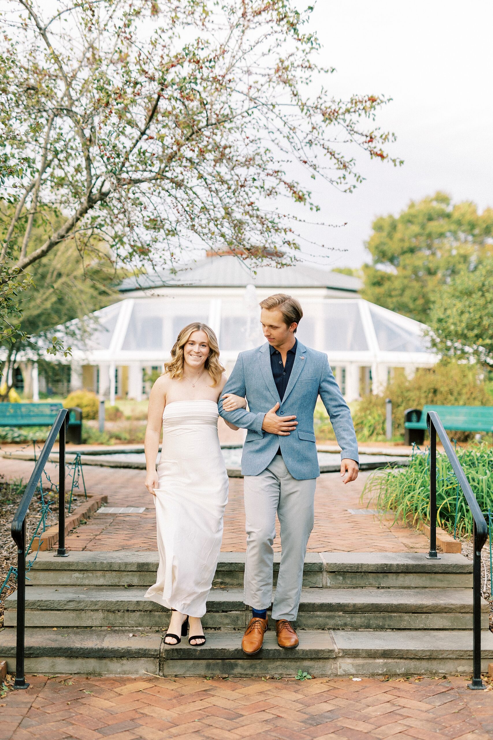 man leads woman down steps away from greenhouse at Daniel Stowe Botanical Garden
