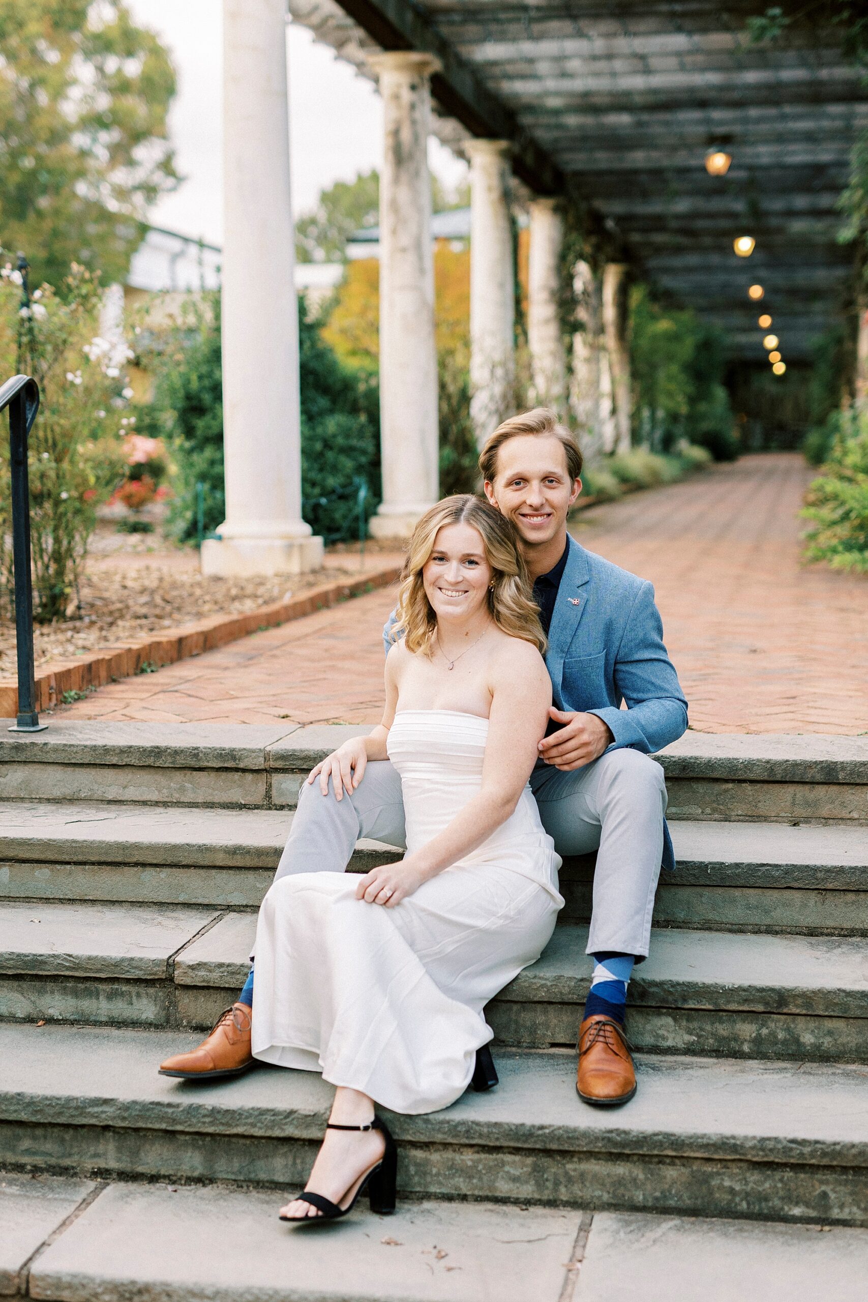 engaged couple sits on steps inside Daniel Stowe Botanical Garden