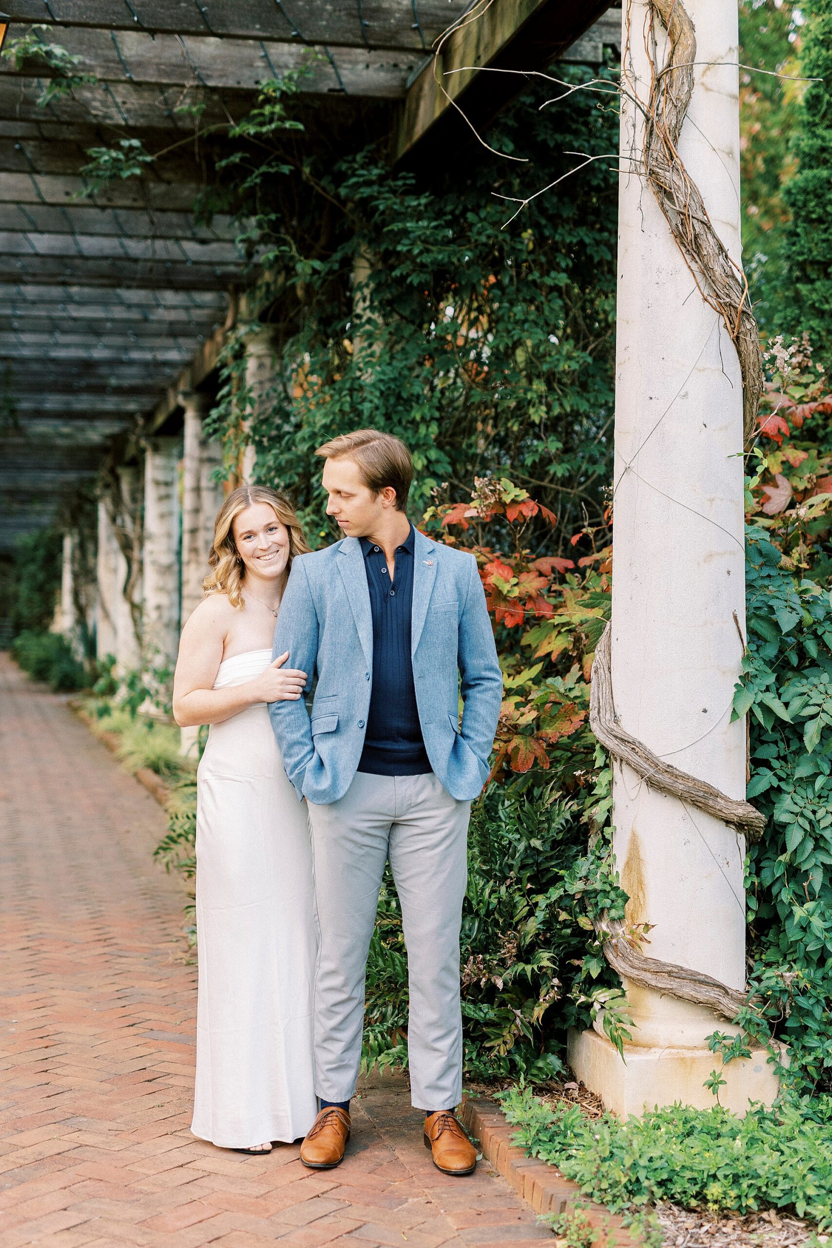 woman in white dress stands behind man in suit jacket 