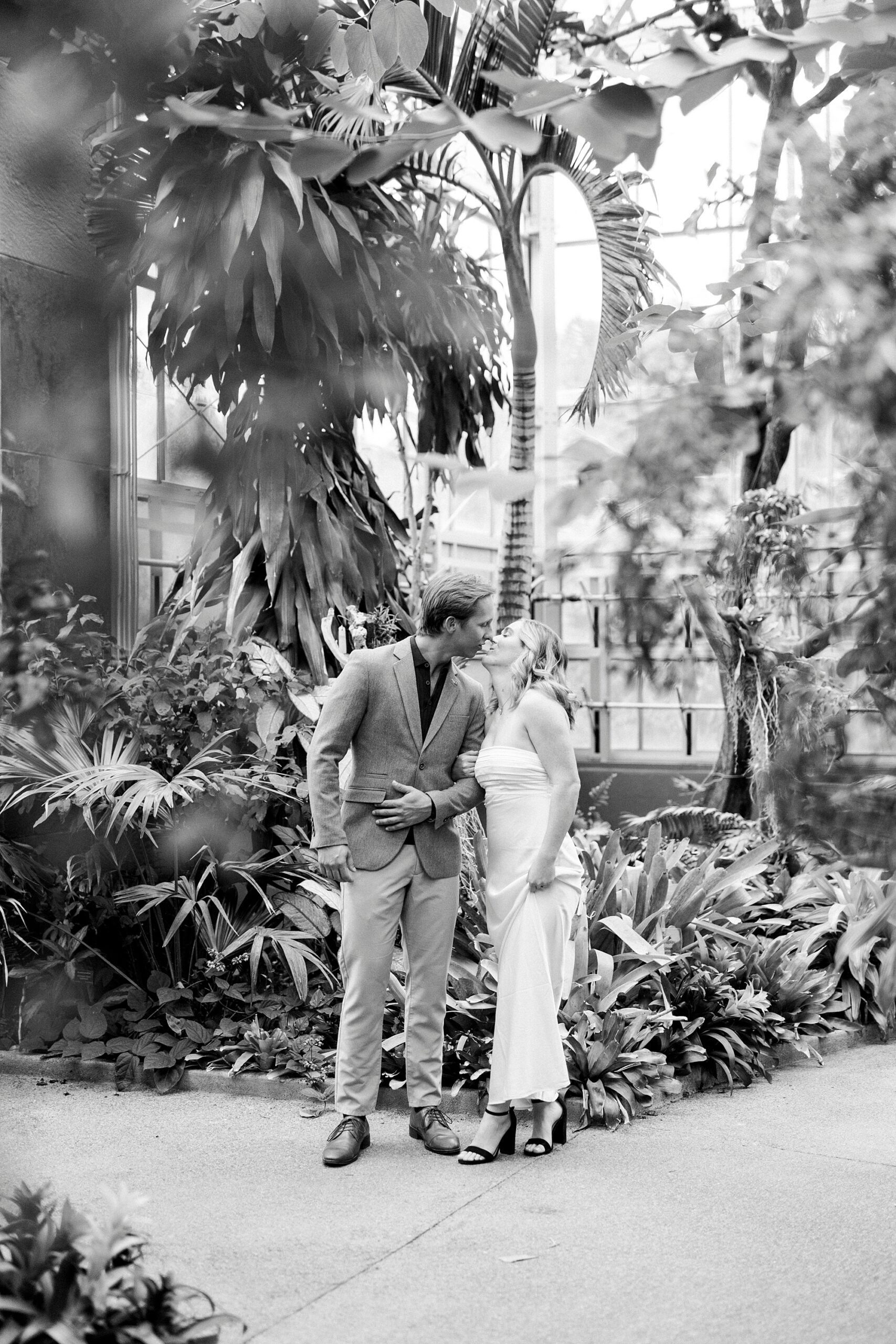 man and woman kiss during engagement photos in biome