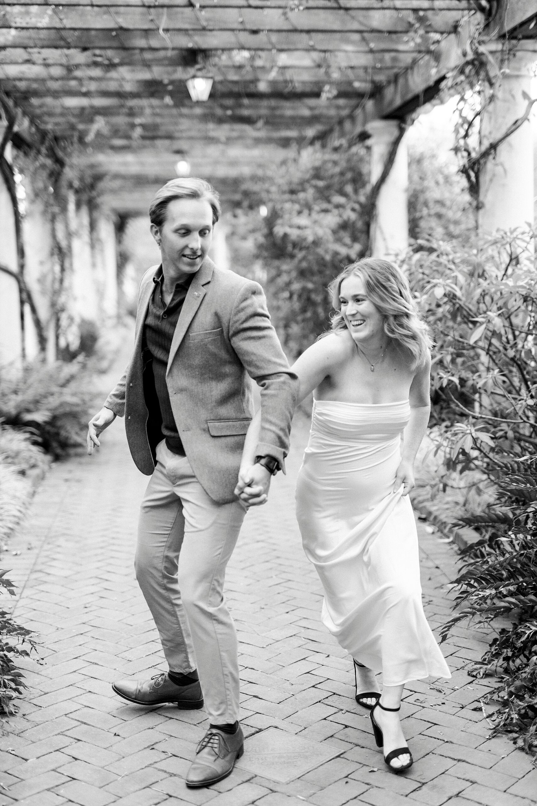 couple holds hands running through walkway at Daniel Stowe Botanical Garden