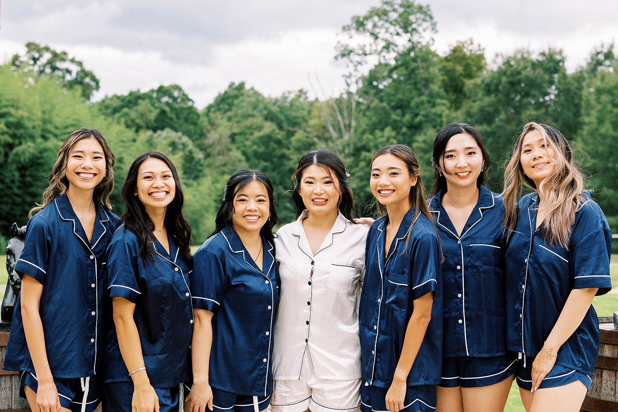 bride poses with bridesmaids in matching blue and white pajamas 