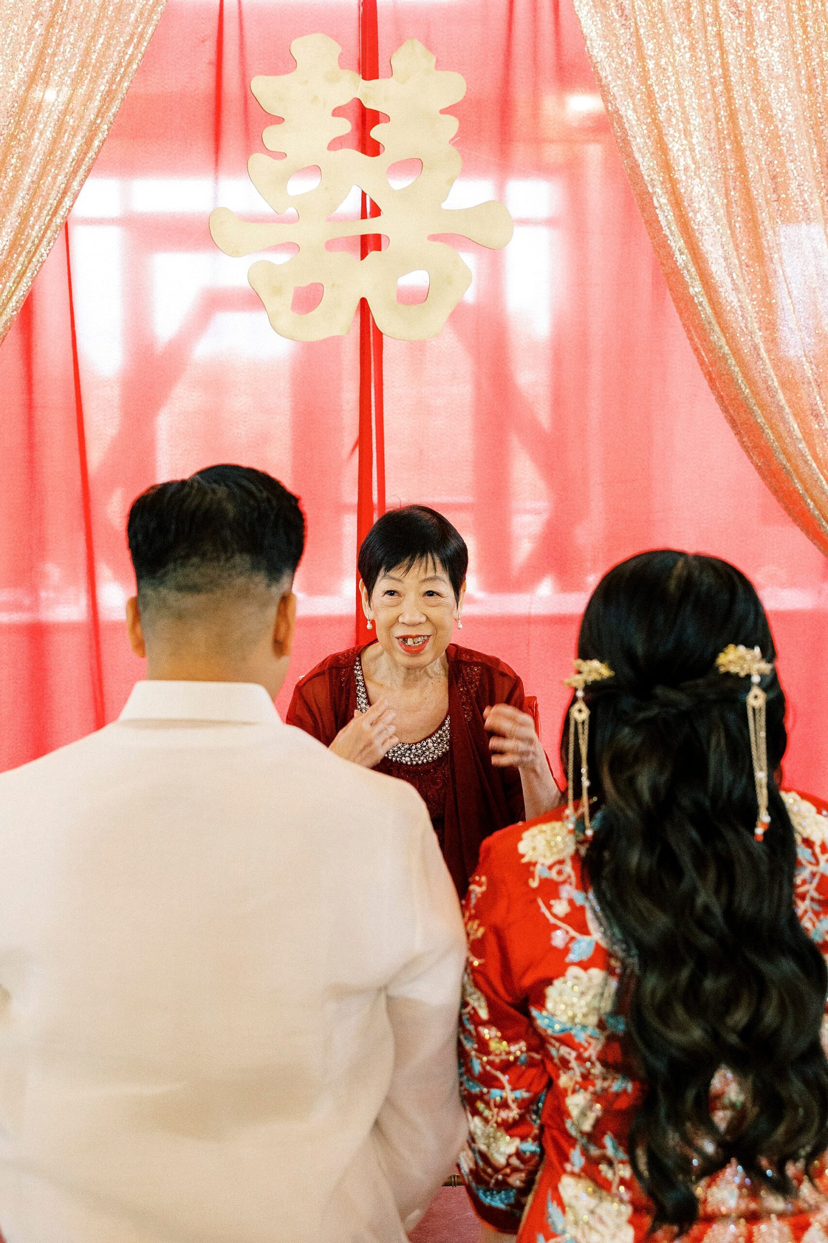 bride and groom speak with mother during Chinese tea ceremony 