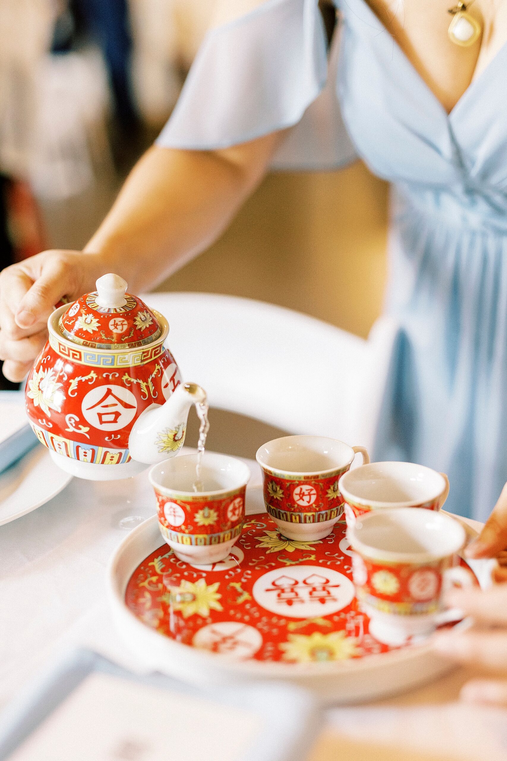 bridesmaid in blue gown pours tea for Chinese tea ceremony 