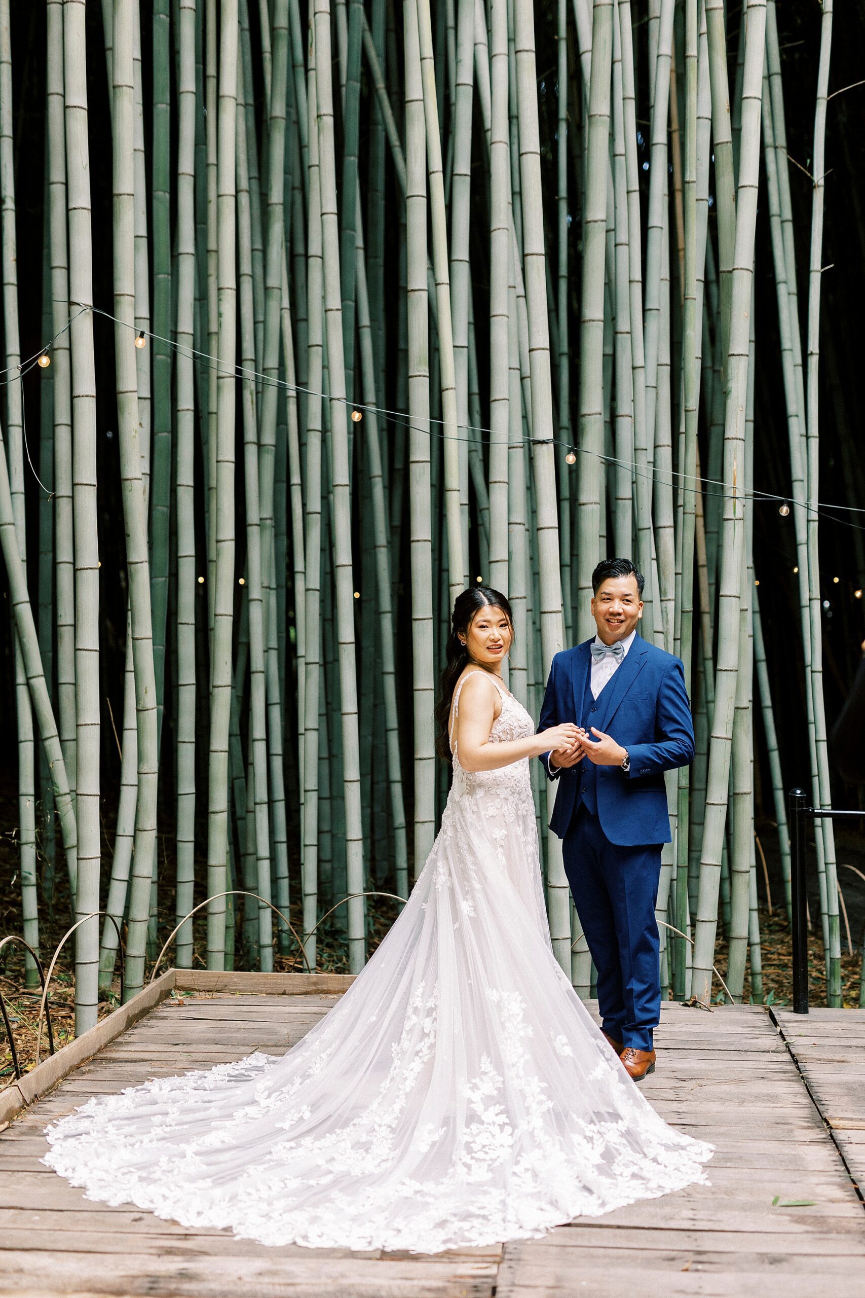 bride and groom hold hands standing inside bamboo forest at Camelot Meadows