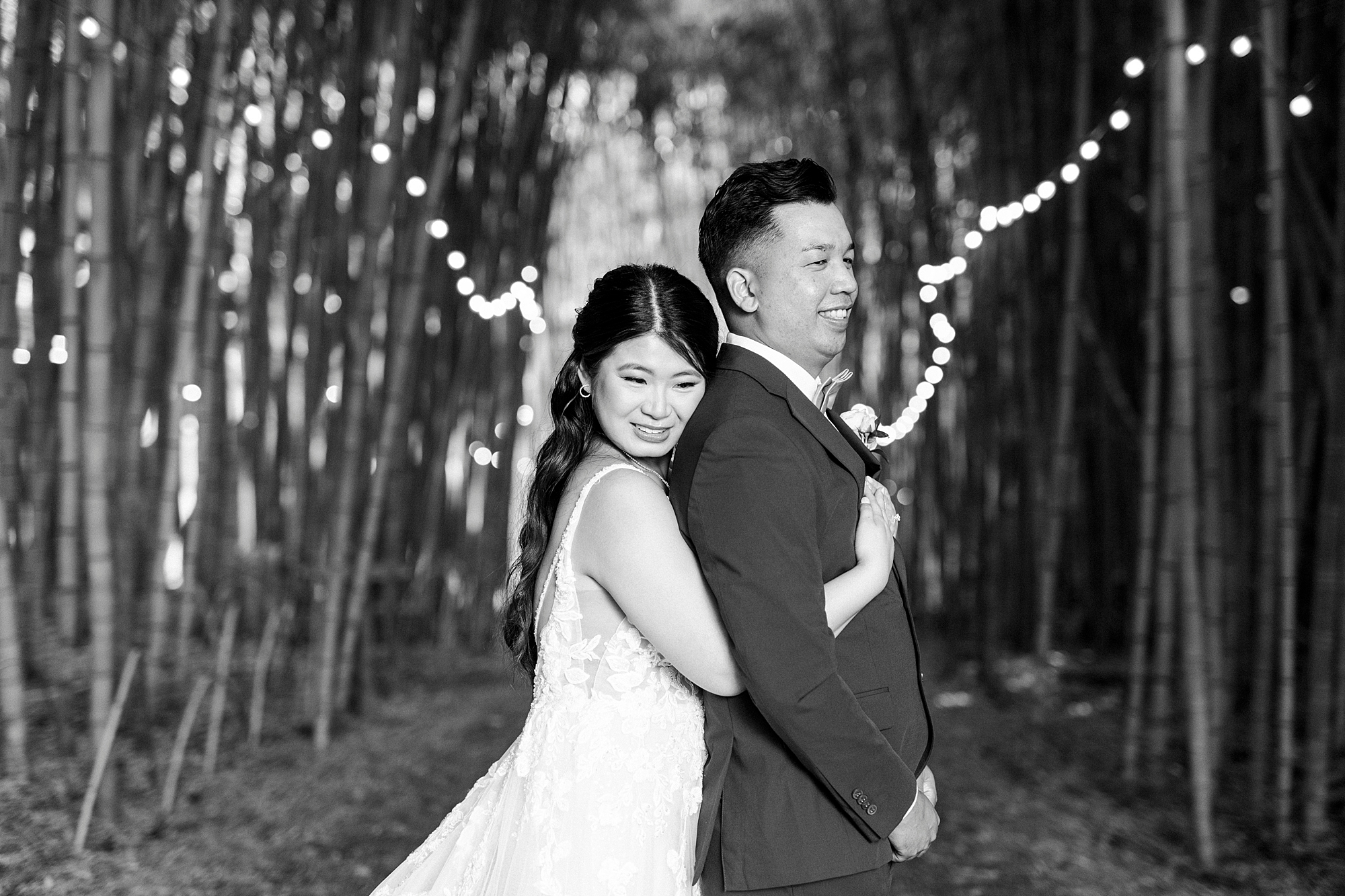bride hugs groom inside bamboo forest at Camelot Meadows with fairly lights 