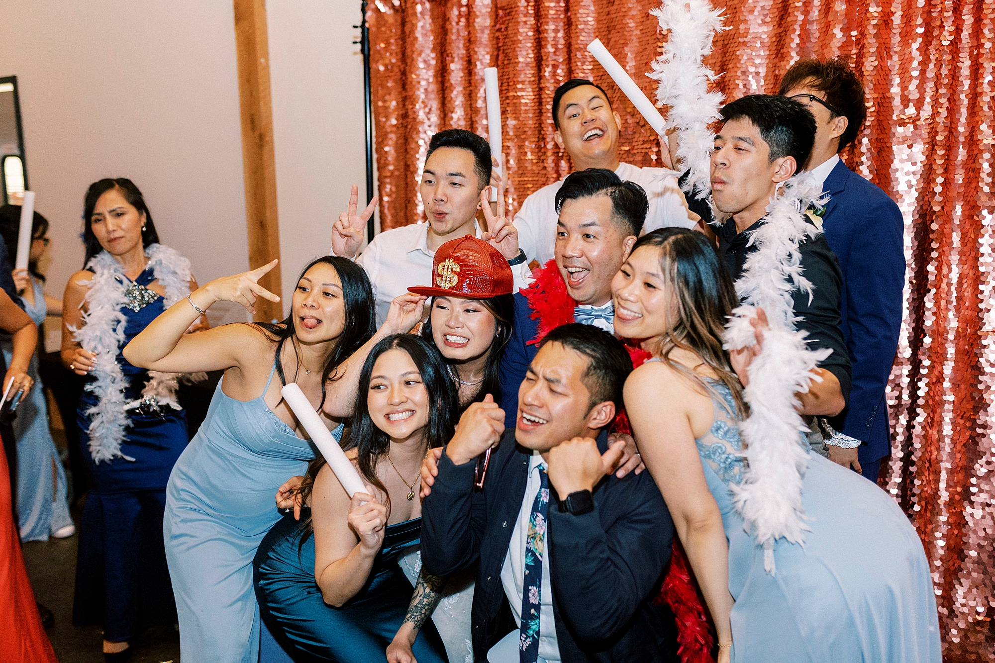 bride and groom pose with wedding party in photo booth 