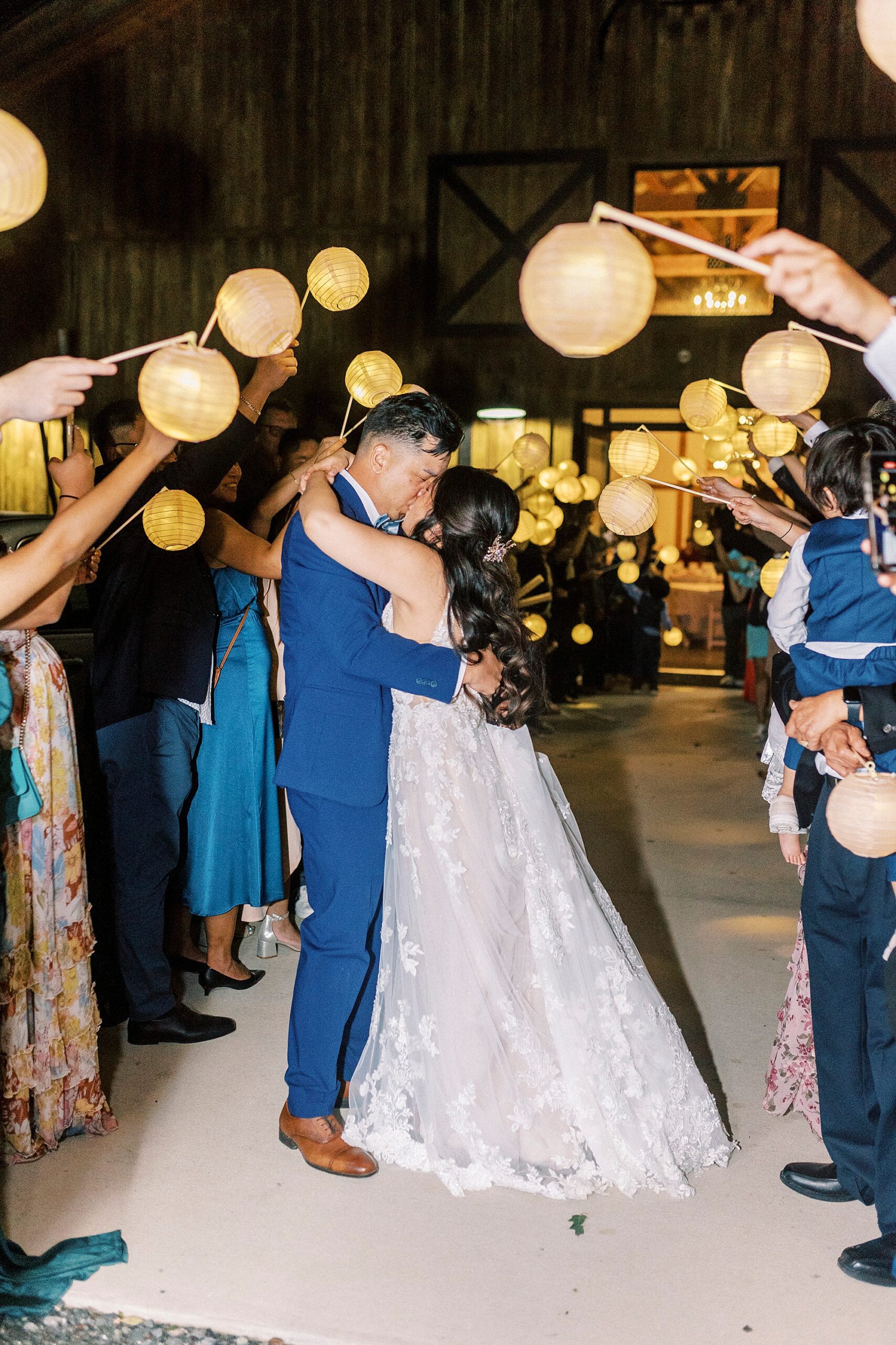 bride and groom kiss leaving Camelot Meadows with traditional lanterns around them