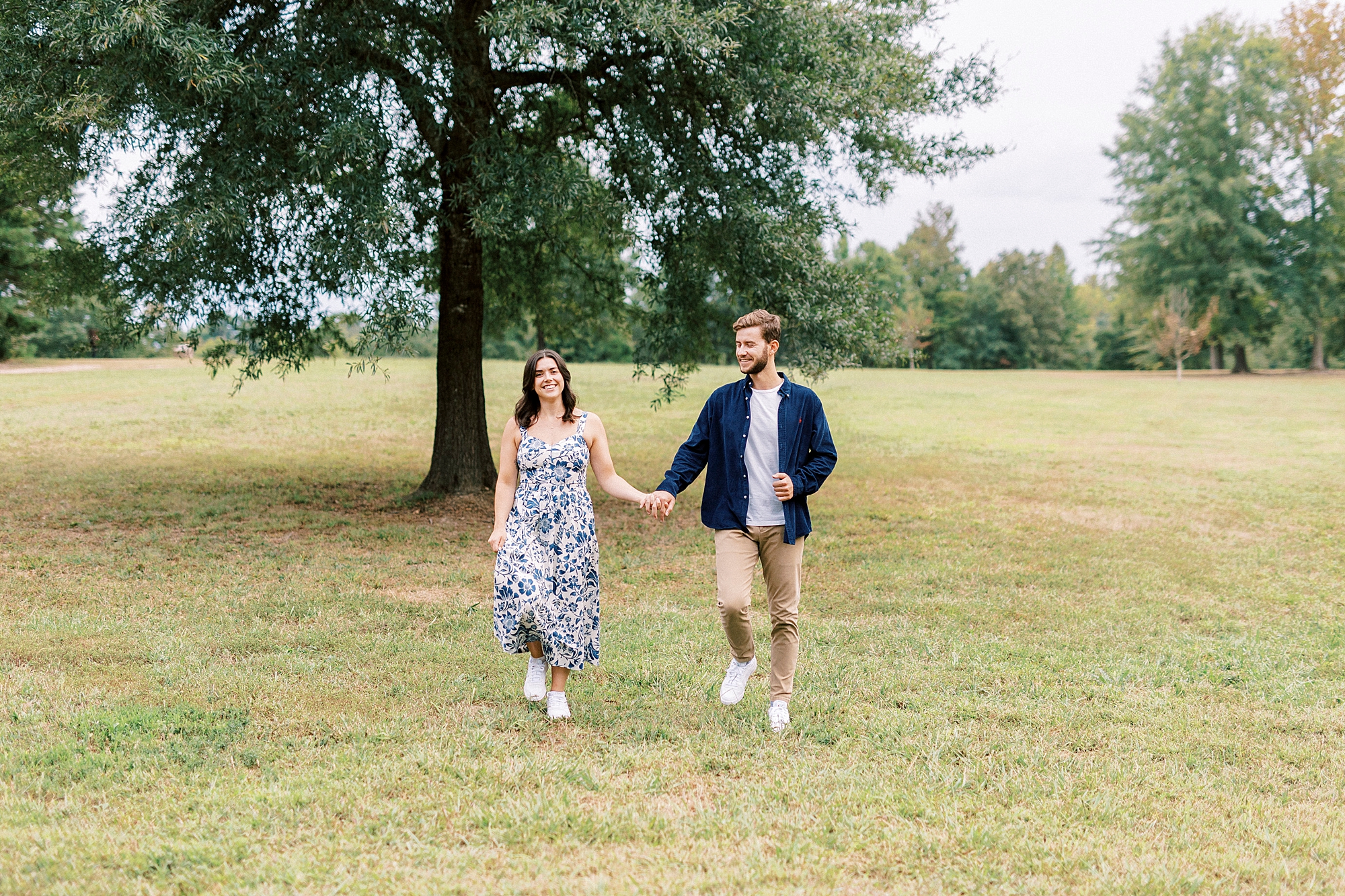 husband and wife hold hands walking down ridge in Rob Wallace Park