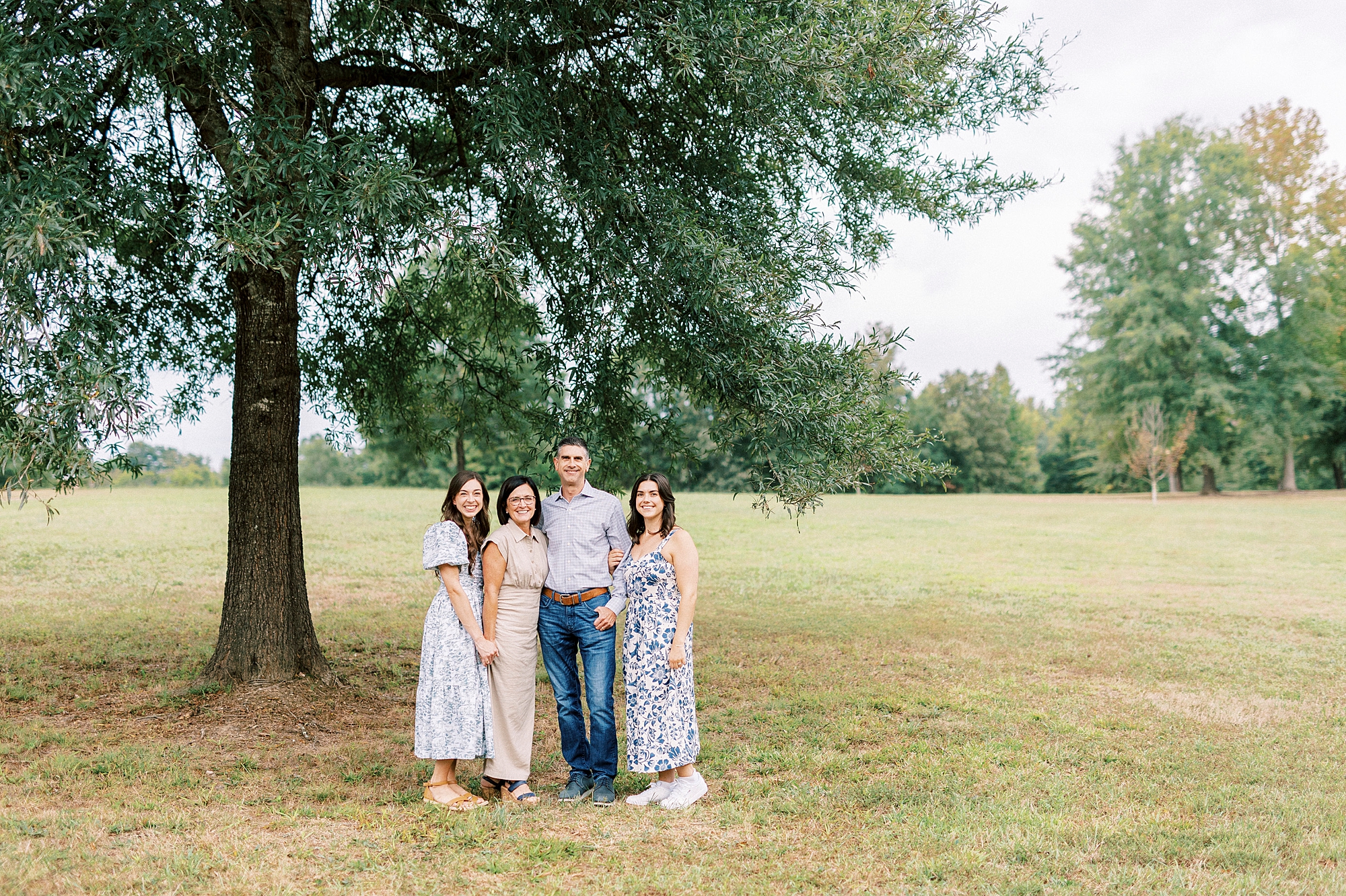 parents stand with two daughters under tree in Rob Wallace Park