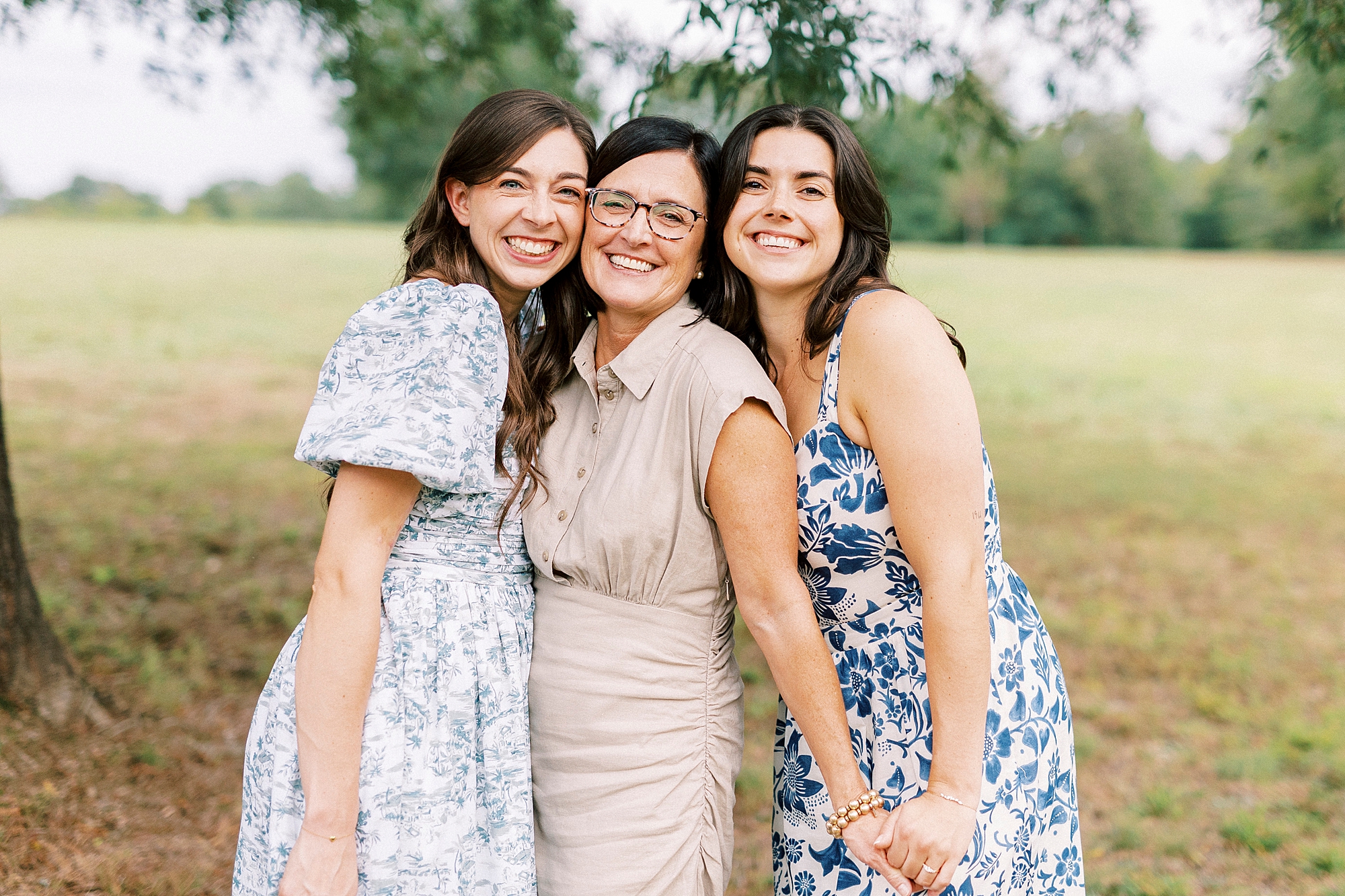 mom stands between two daughters holding their hands