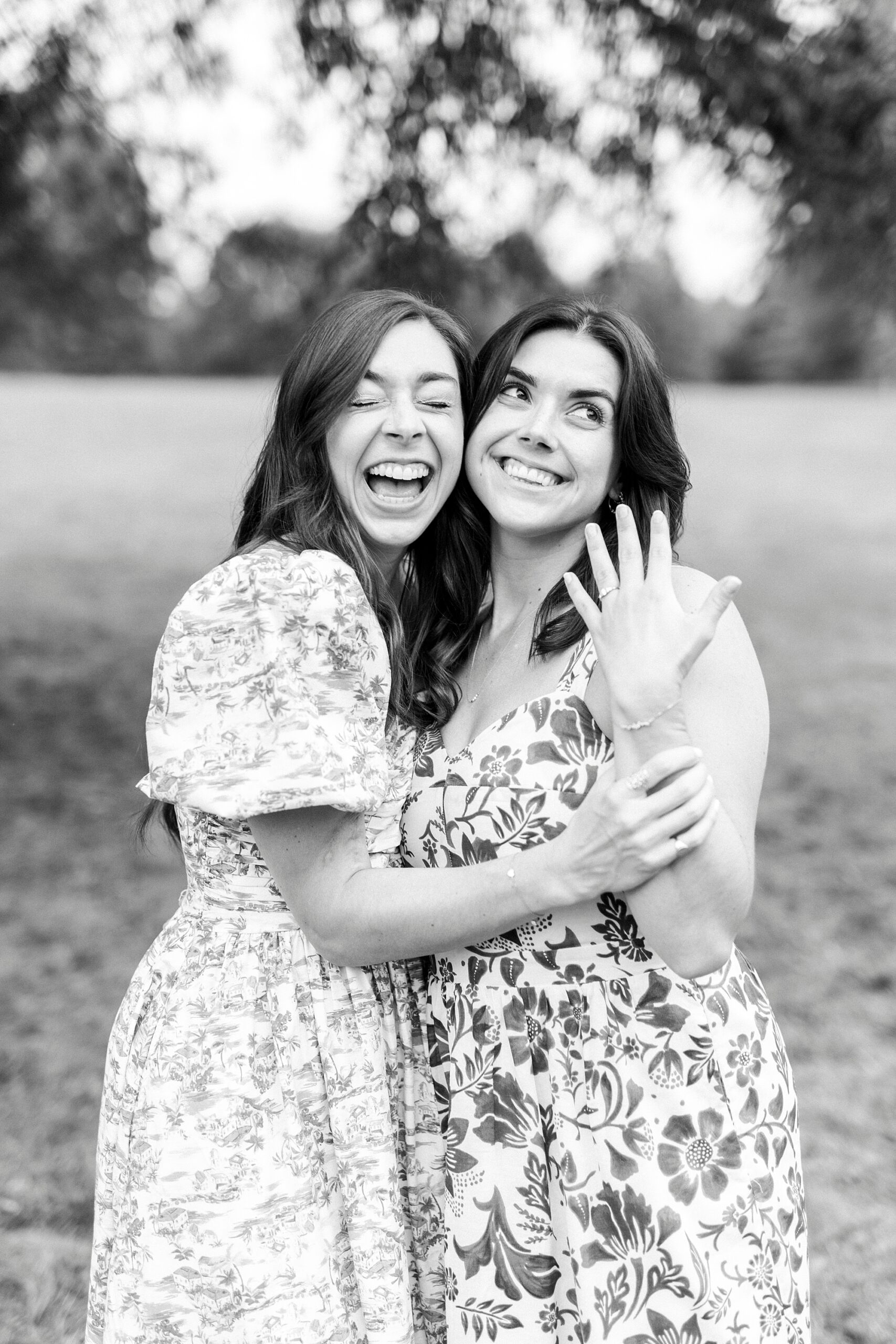 sisters hug while one shows off wedding ring