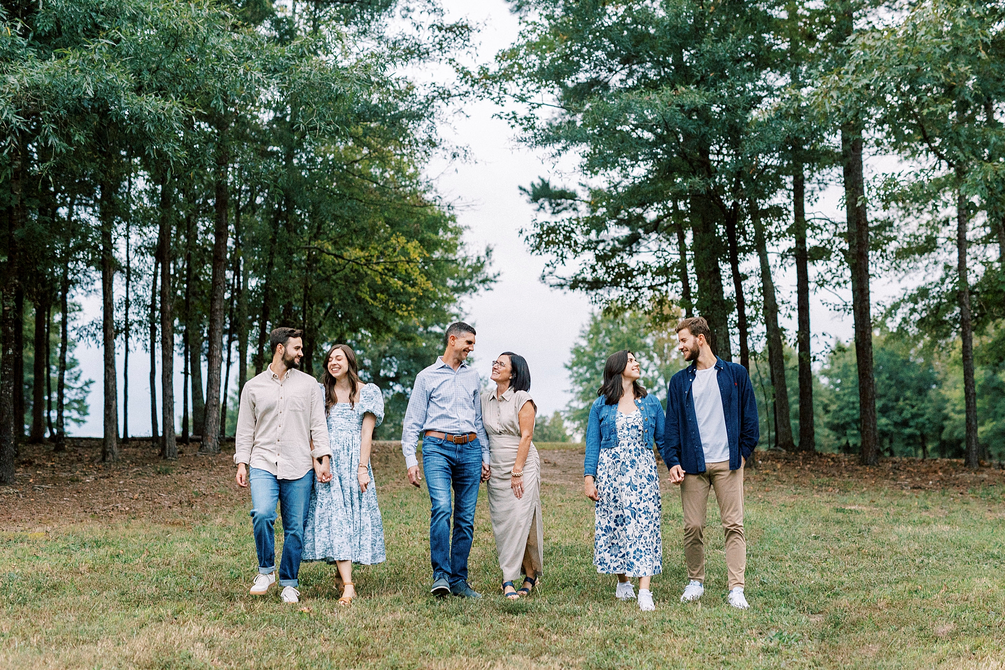 parents and adult daughters smile with spouses in a line
