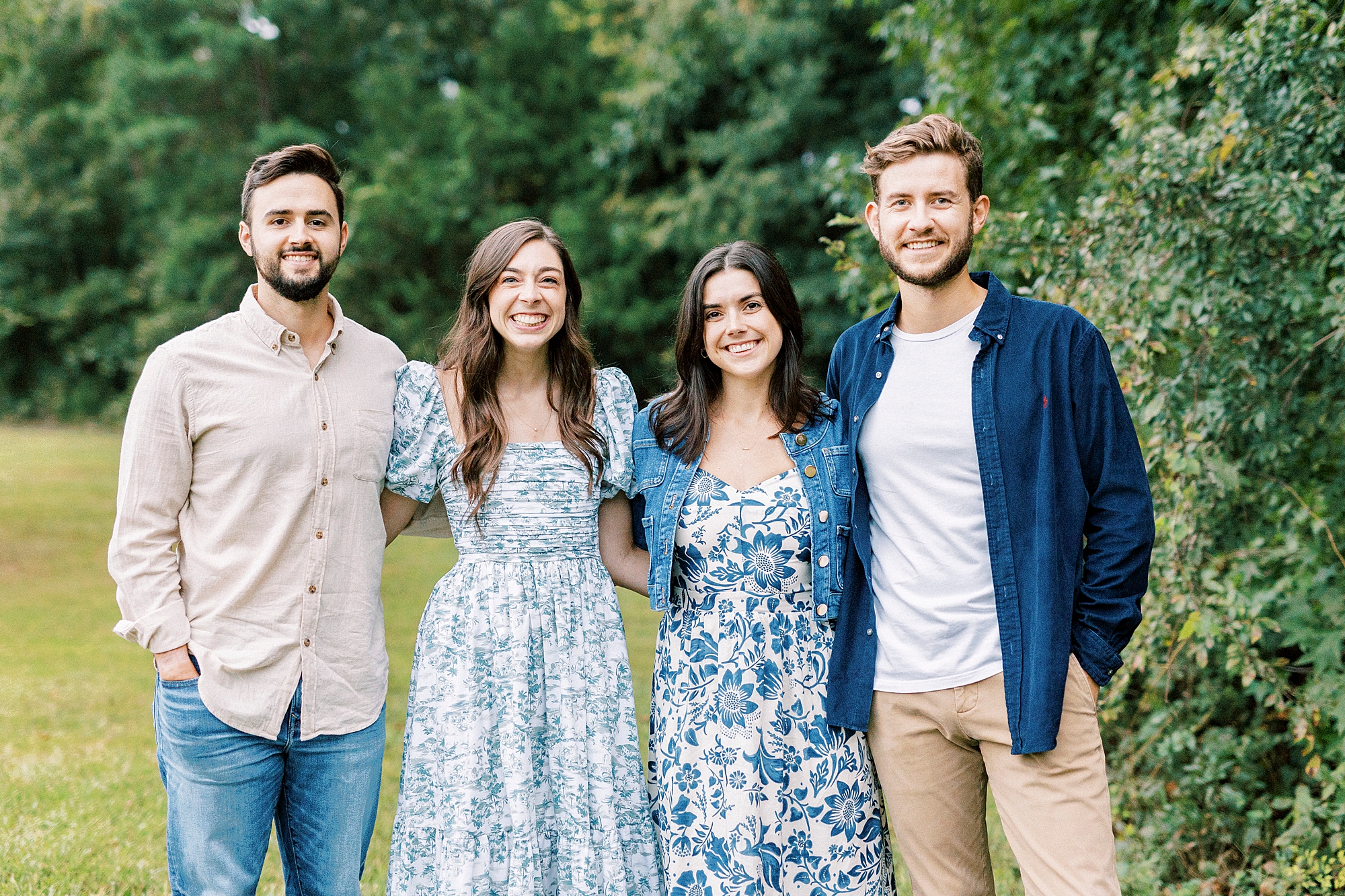 sisters hug with husbands on the other sides of them