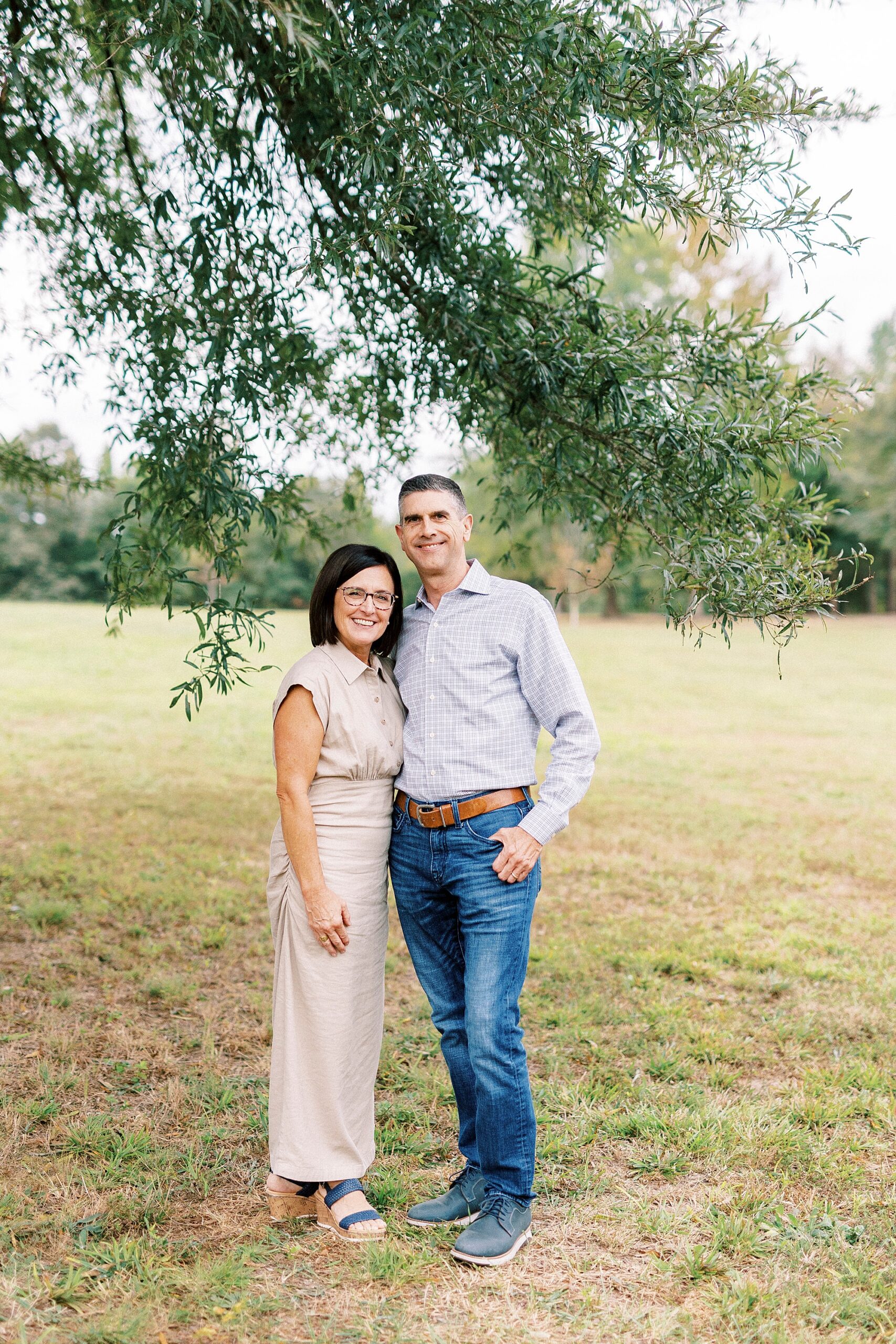 mom and dad hug under tree during family photos at Rob Wallace Park
