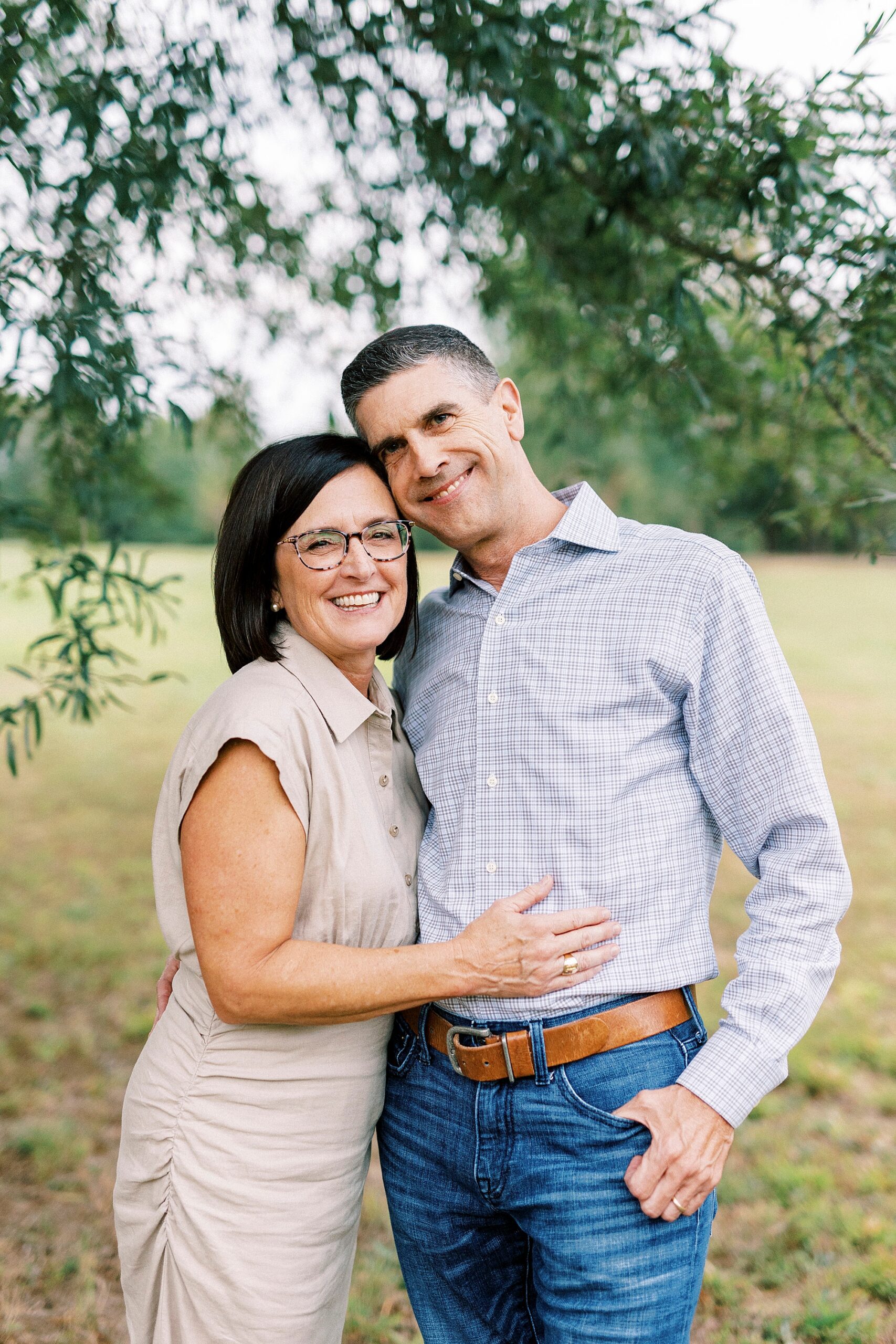 husband and wife hug under tree in Midland NC park