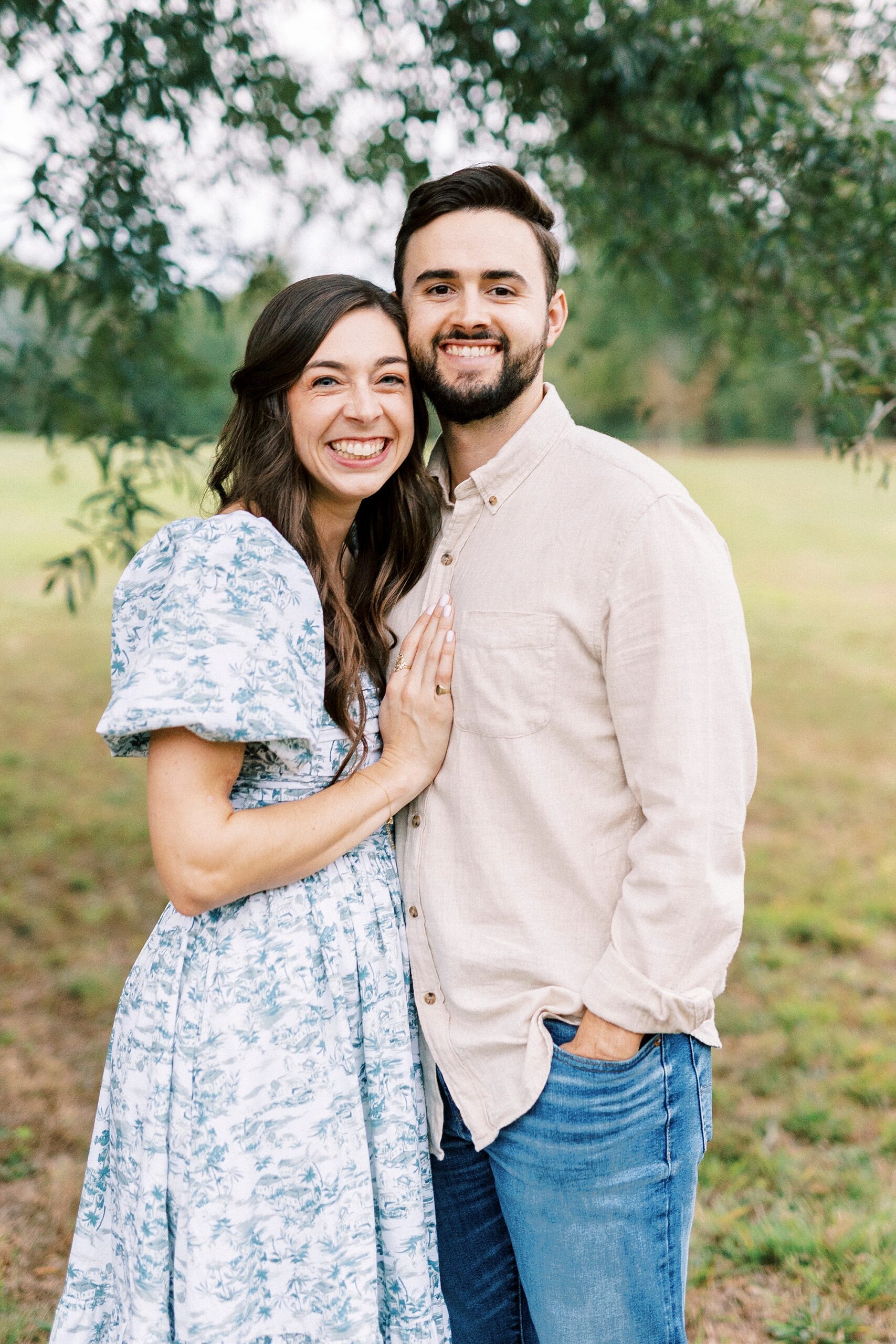 young woman leans into husband under tree at Rob Wallace Park