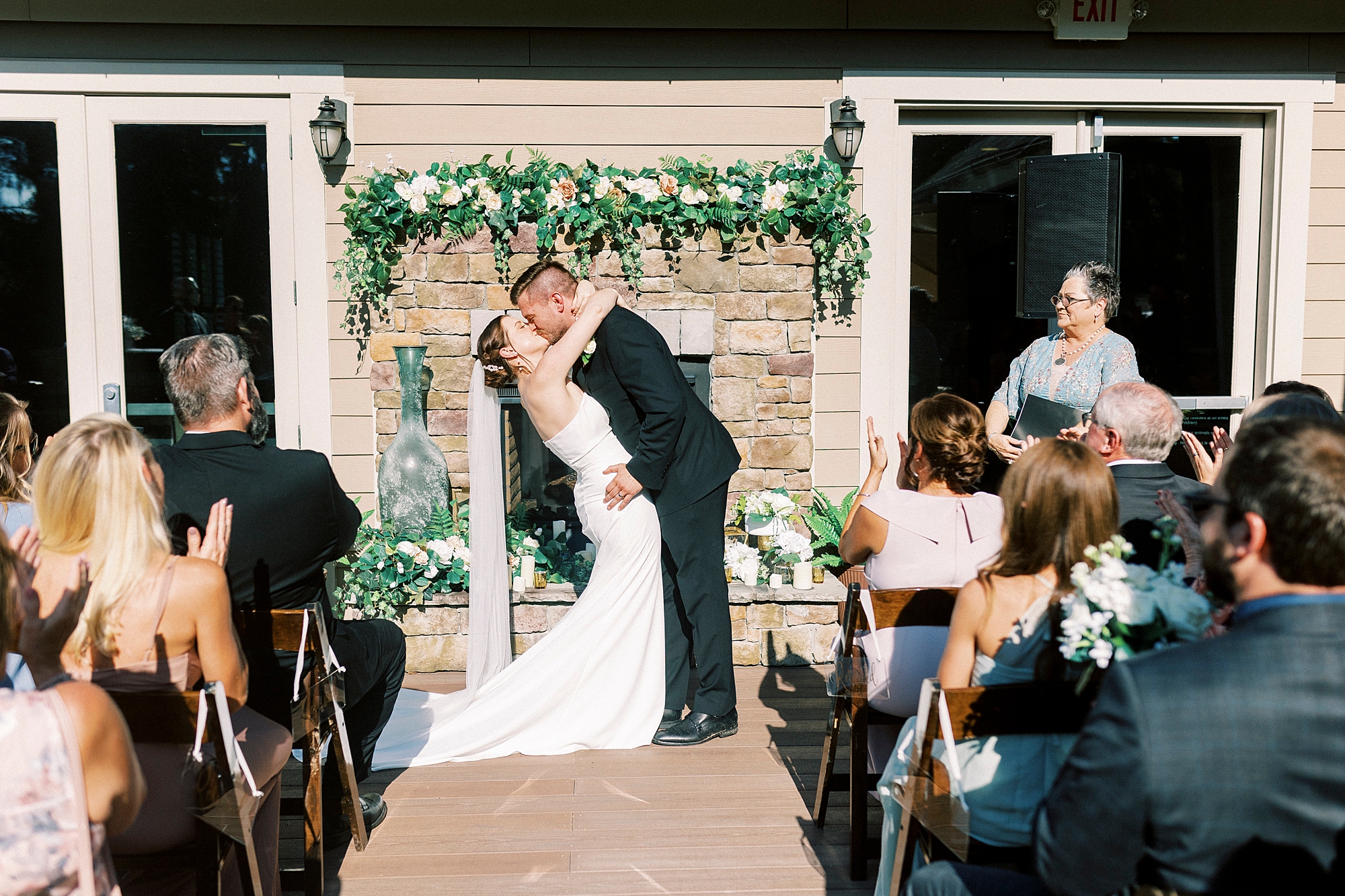 bride and groom kiss in front of brick fireplace at Palisades Country Club