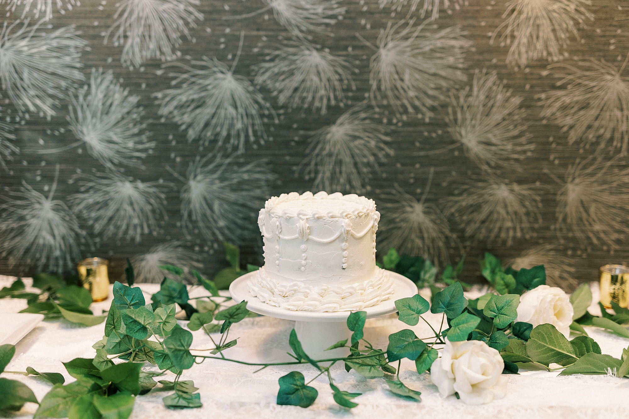single tiered wedding cake with white flowers around it