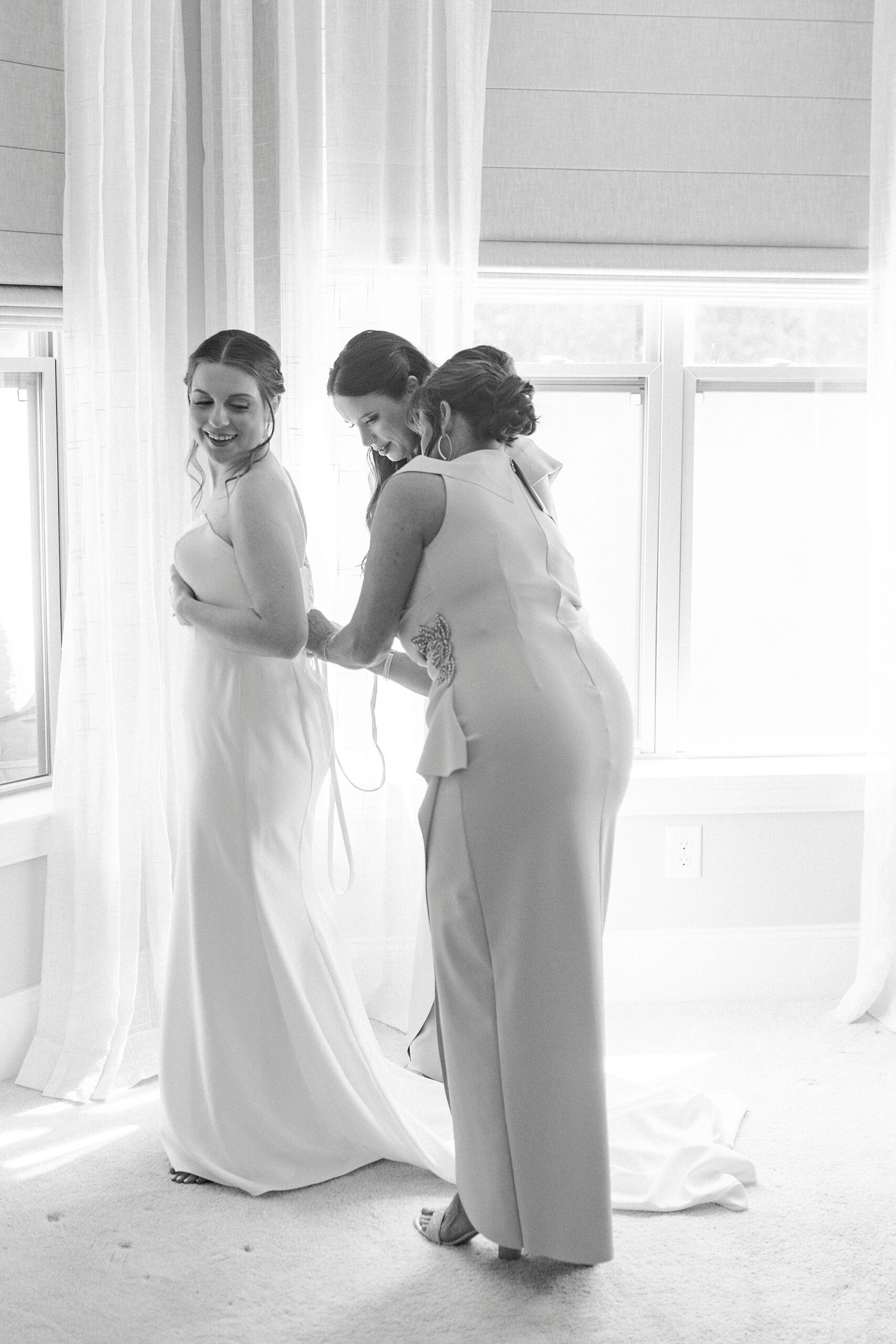 family helps bride into wedding dress 