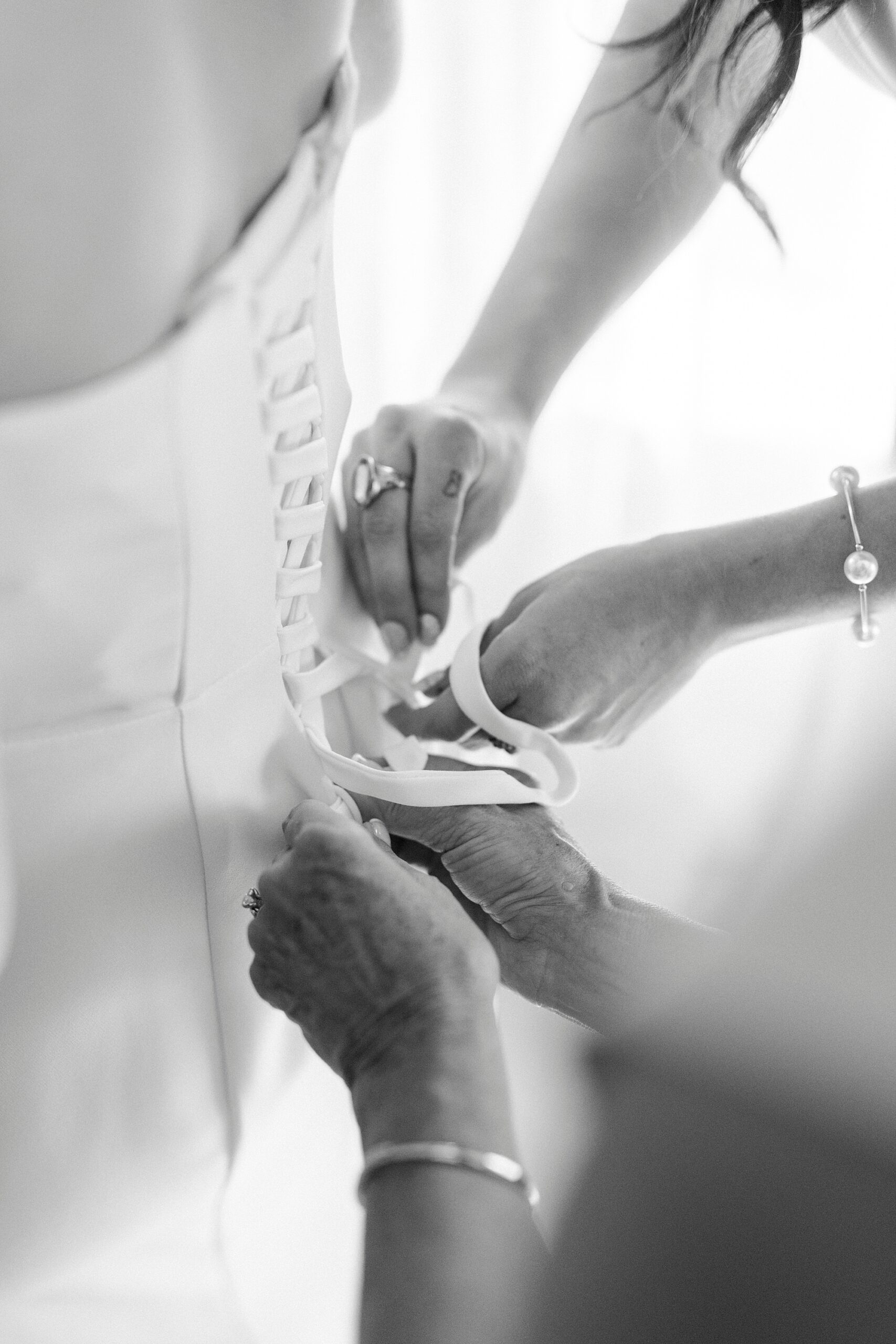 bridesmaid and mother tie up corset of wedding dress