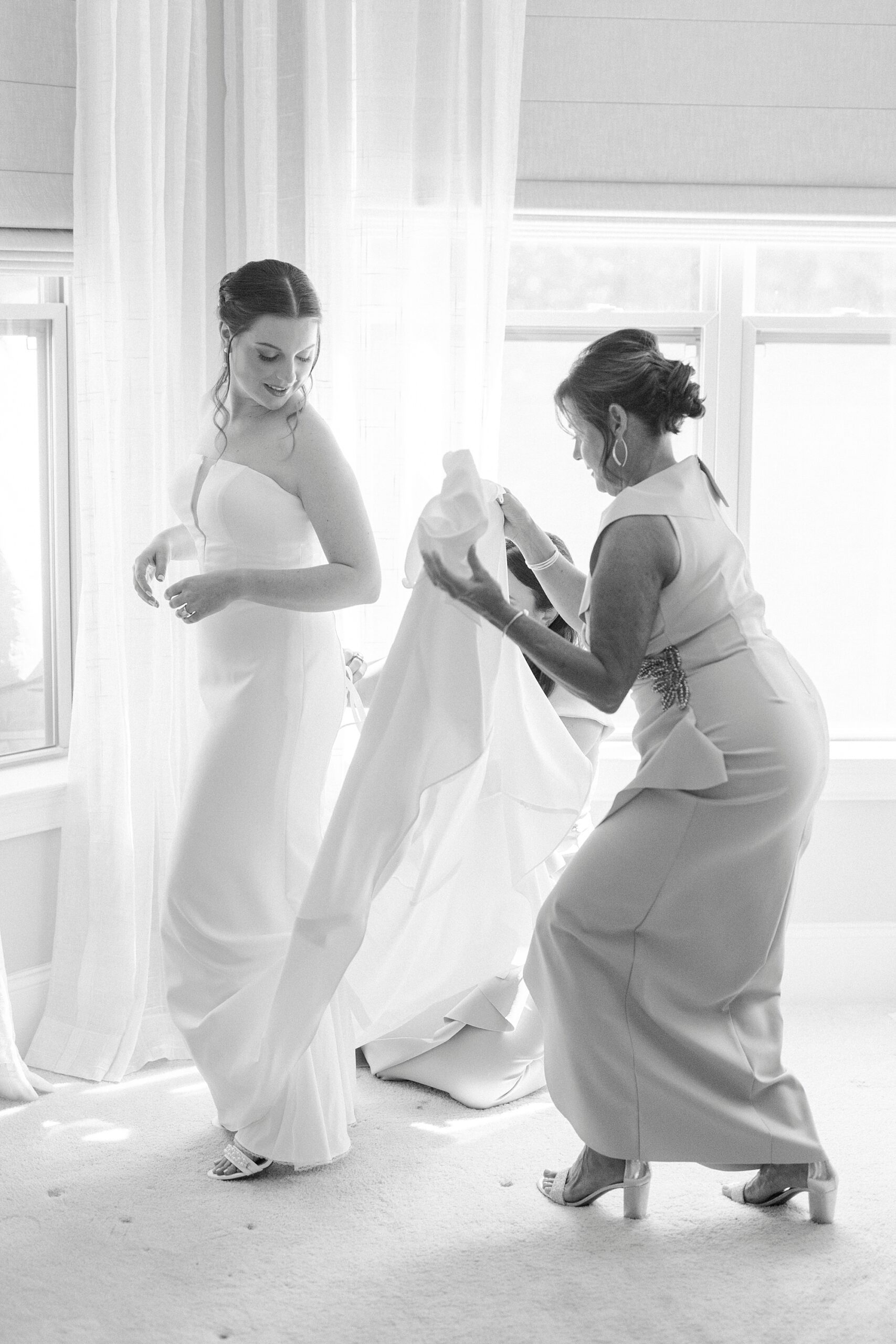 mom fluffs skirt of wedding dress for bride