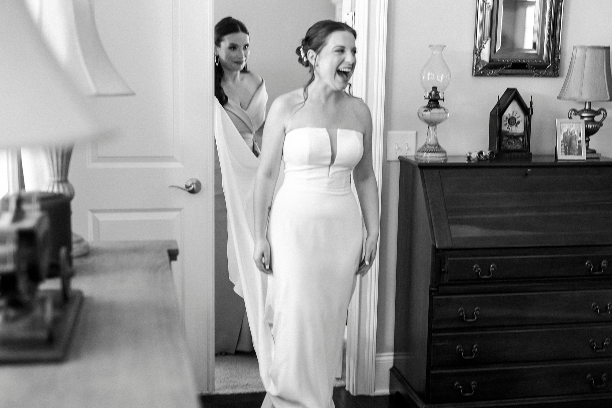bride walks into bedroom showing off dress to family
